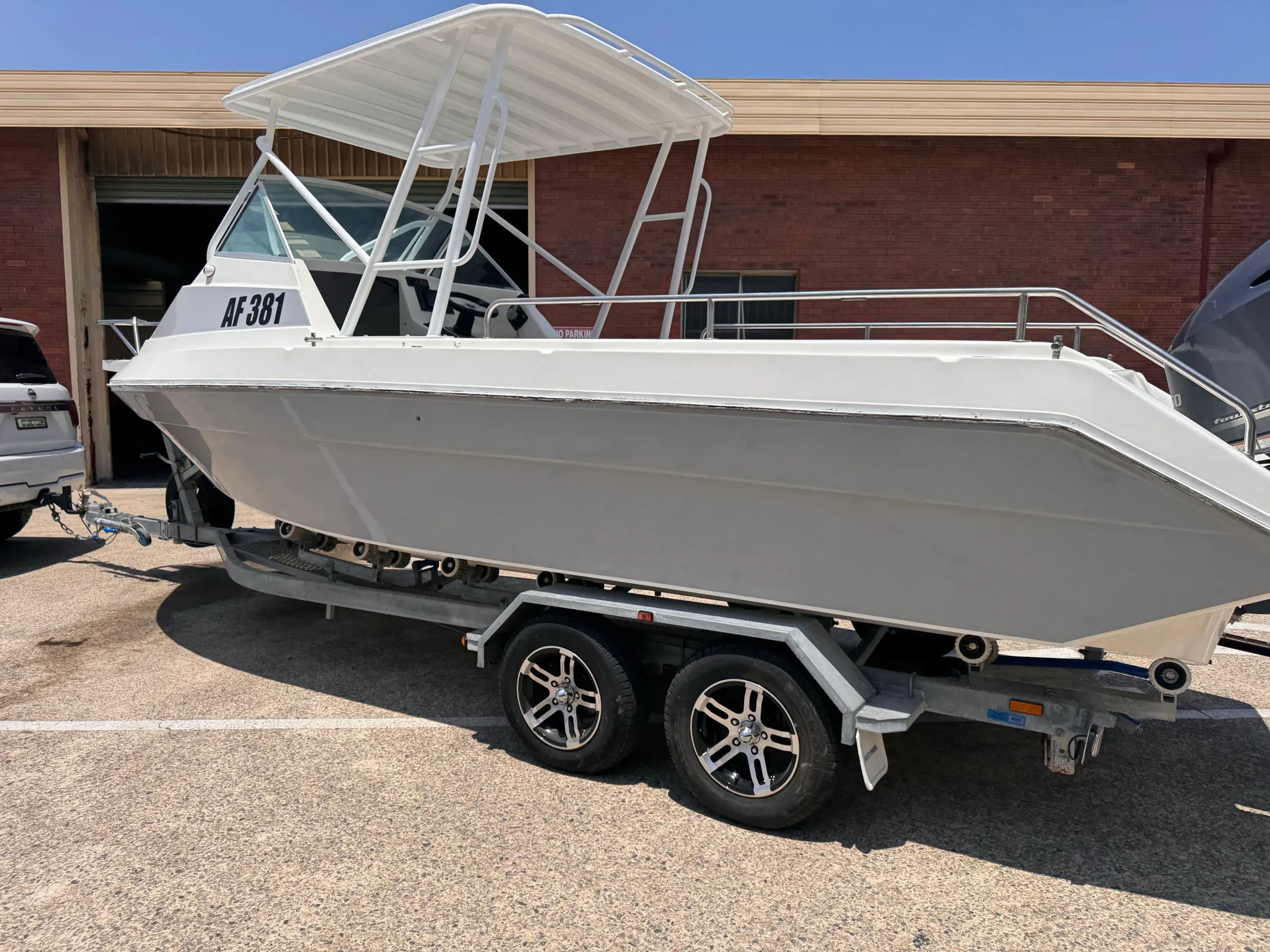 White boat with a grey hull wrap on its trailer outside the workshop