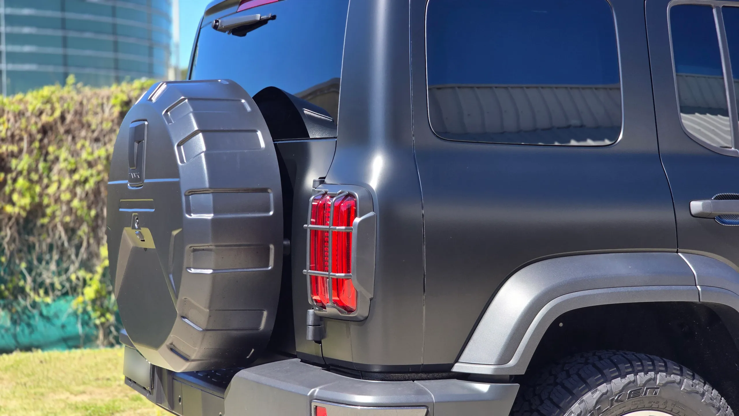 Rear quarter of a satin black GWM Tank 300, showing the spare wheel cover and vertical tail light