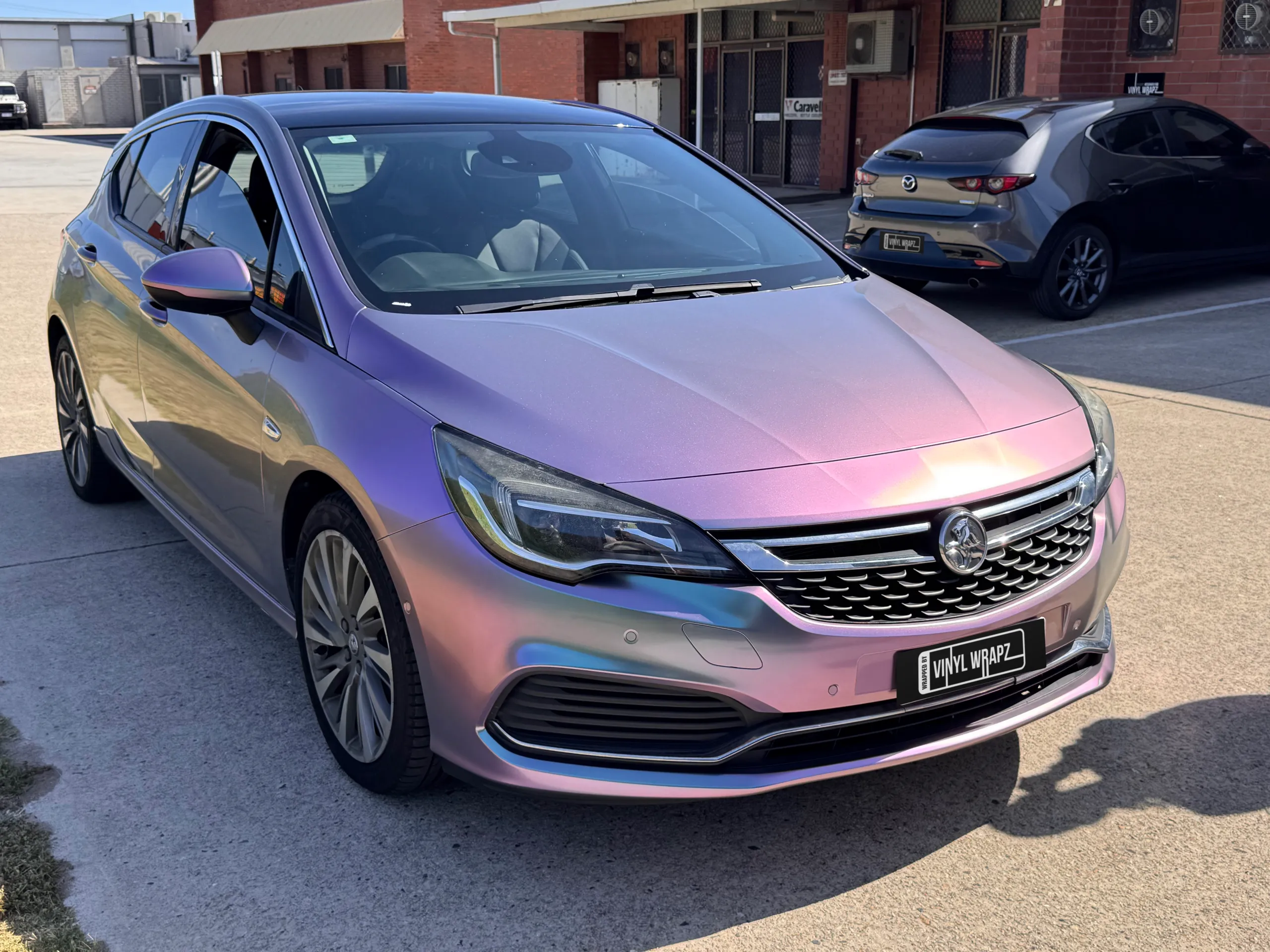 Lavender colour-shift Holden Astra hatchback outside the workshop, front quarter