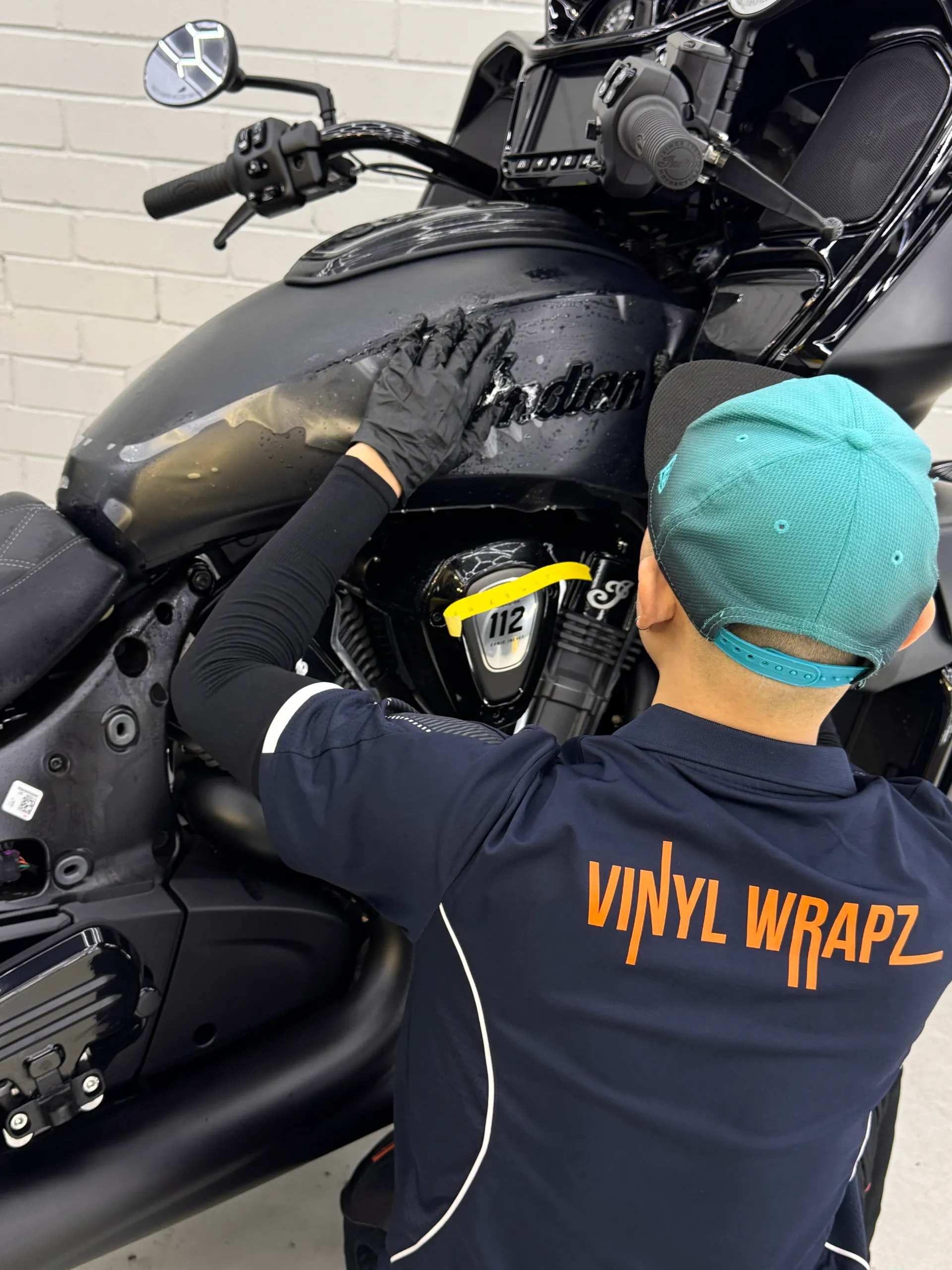 Back-facing installer fitting film around the Indian motorcycle fuel tank