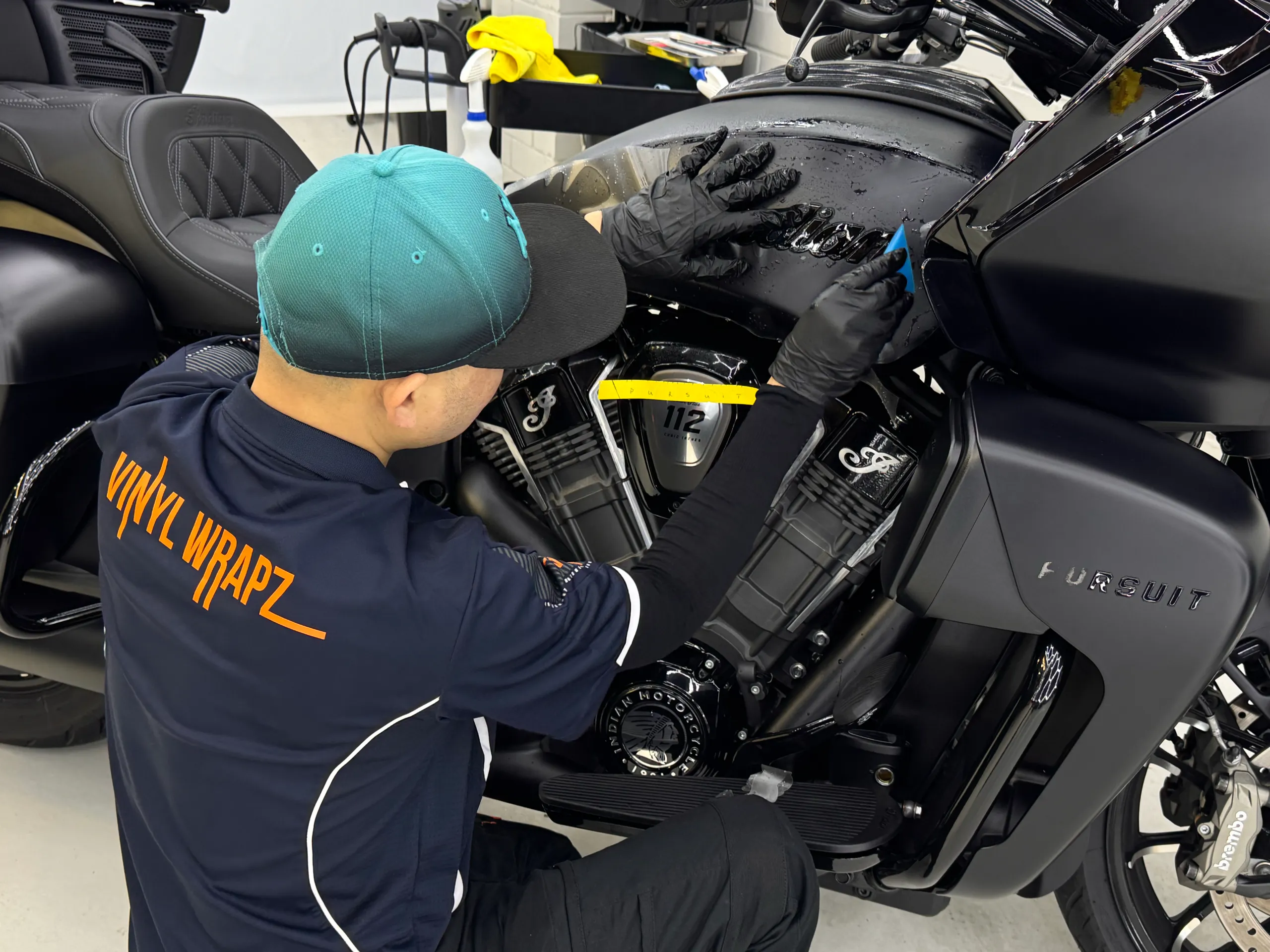 Installer smoothing film over the Indian Pursuit fuel tank above the engine
