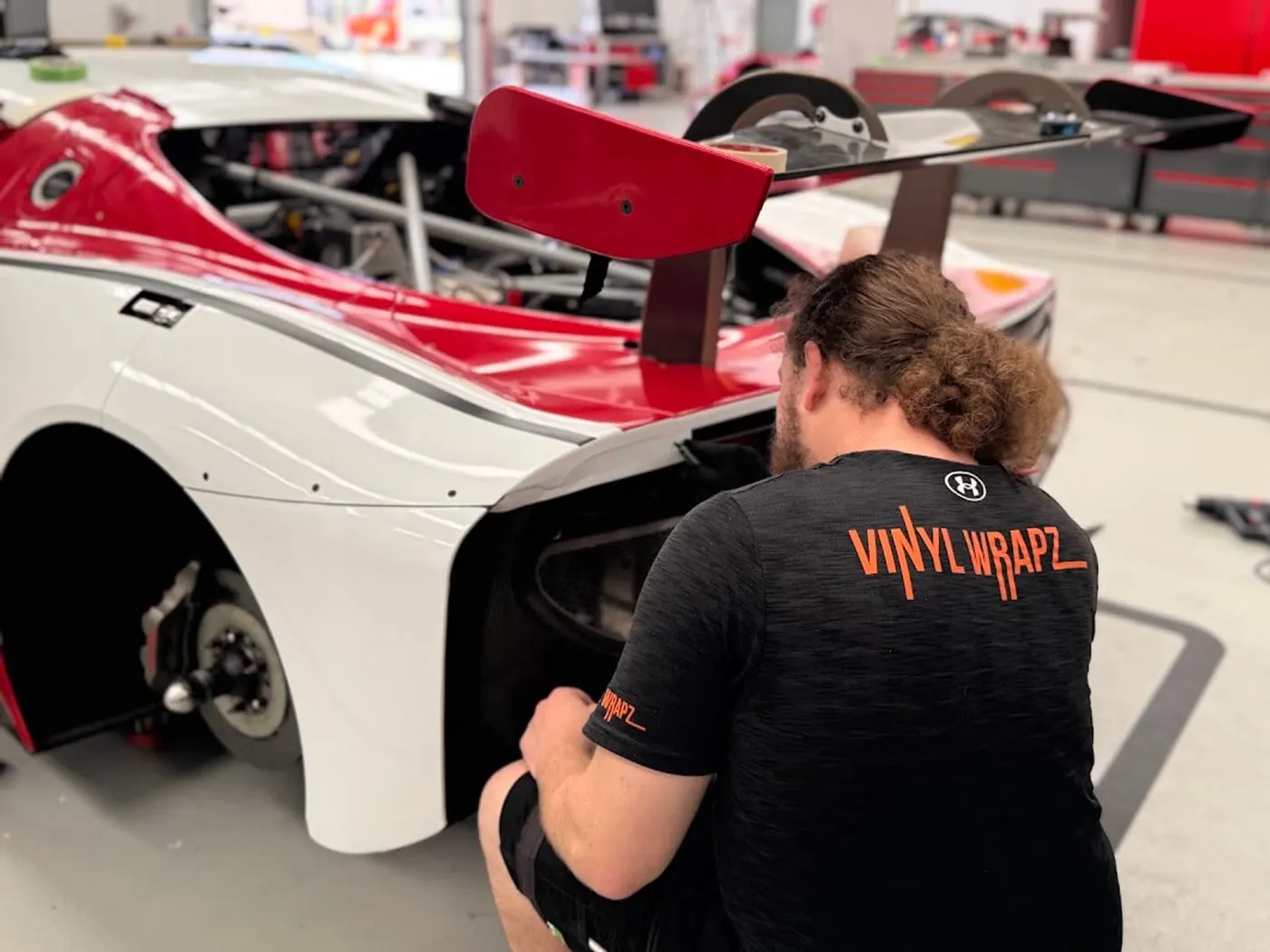 Installer fitting a printed race livery to a white and red race car