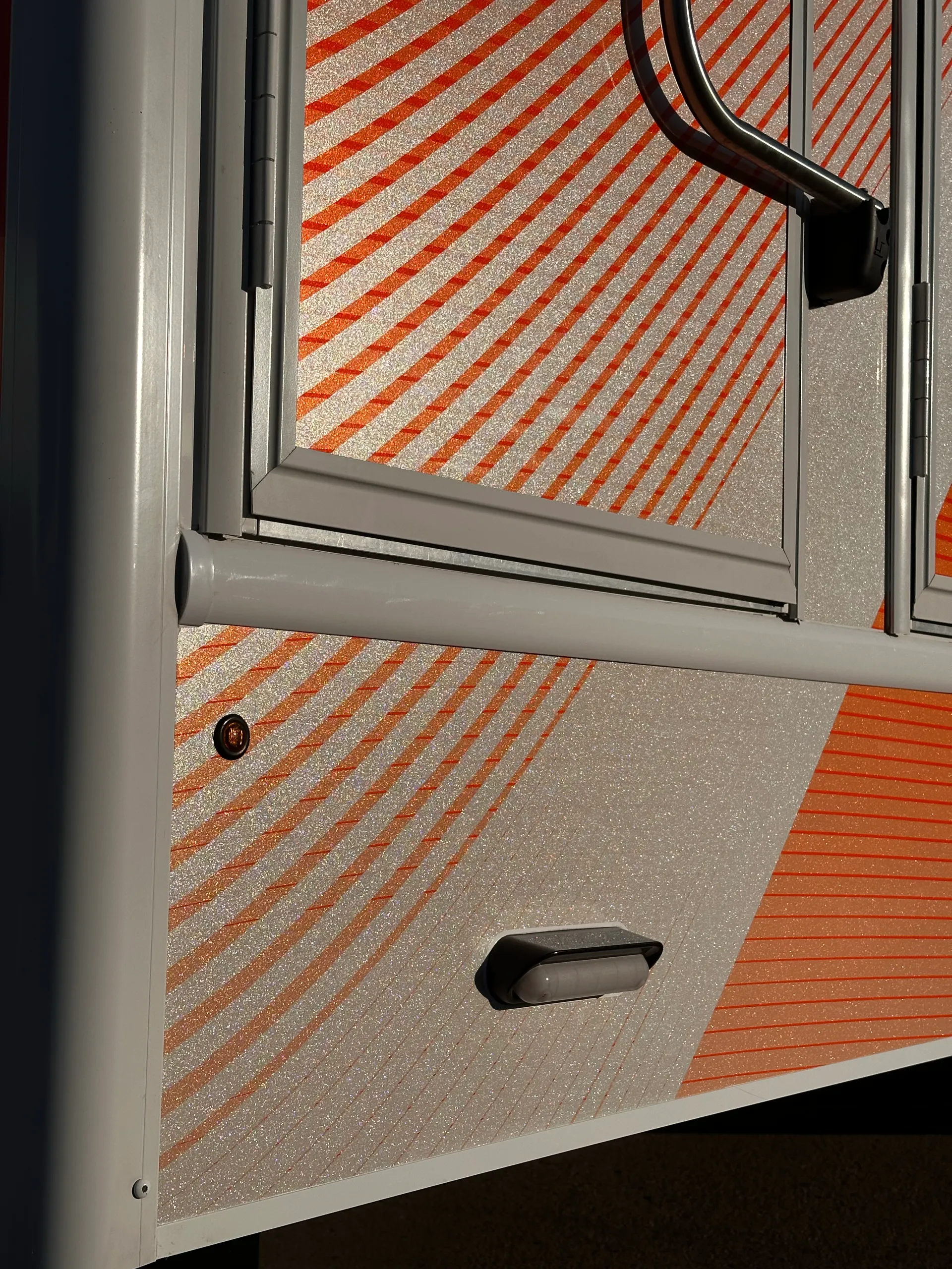 Close-up of the shimmering orange and white trailer wrap around a door and lower side panel