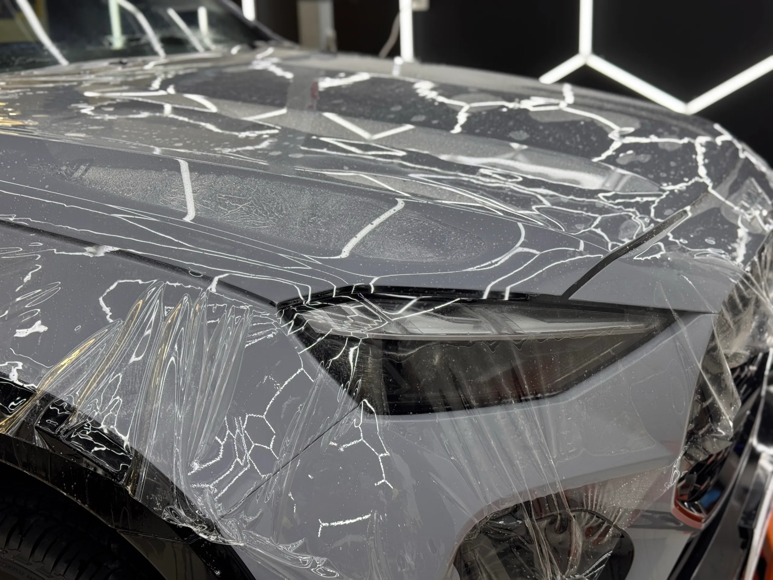 Clear film being fitted across the grey Isuzu MU-X bonnet and front guard