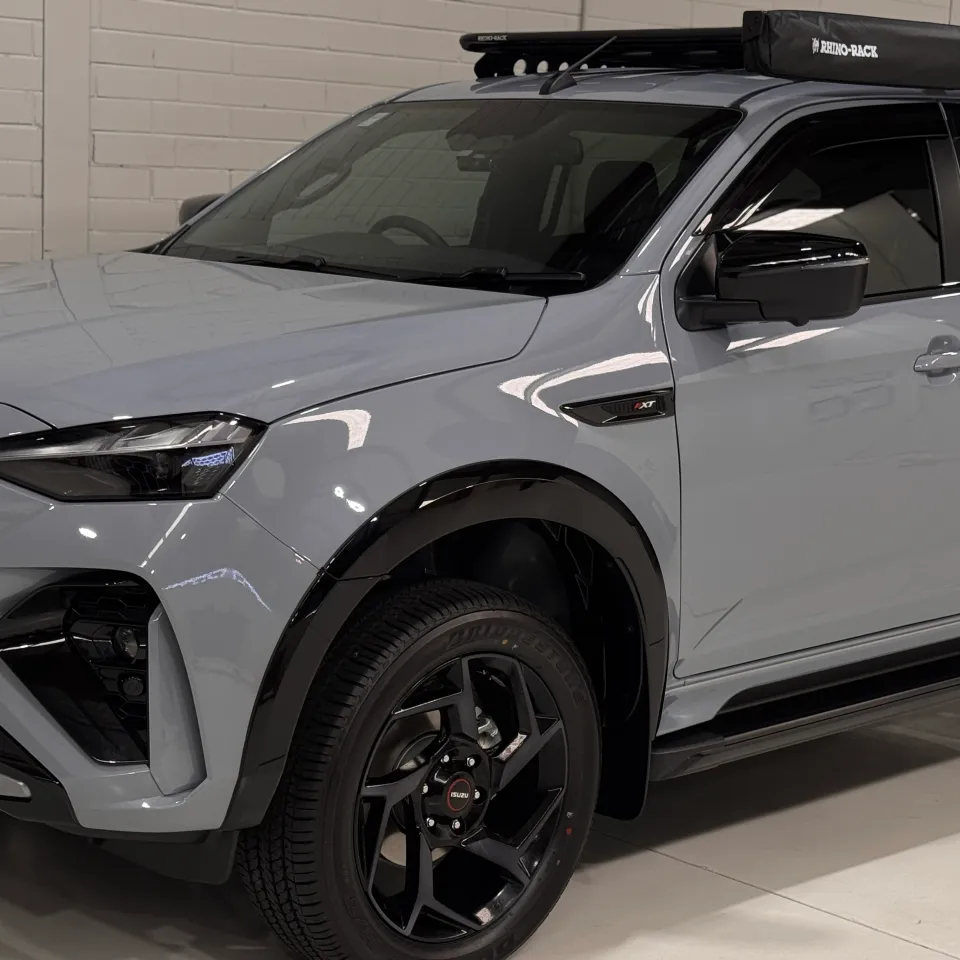 Front quarter and roof rack of a gloss grey Isuzu MU-X in the workshop