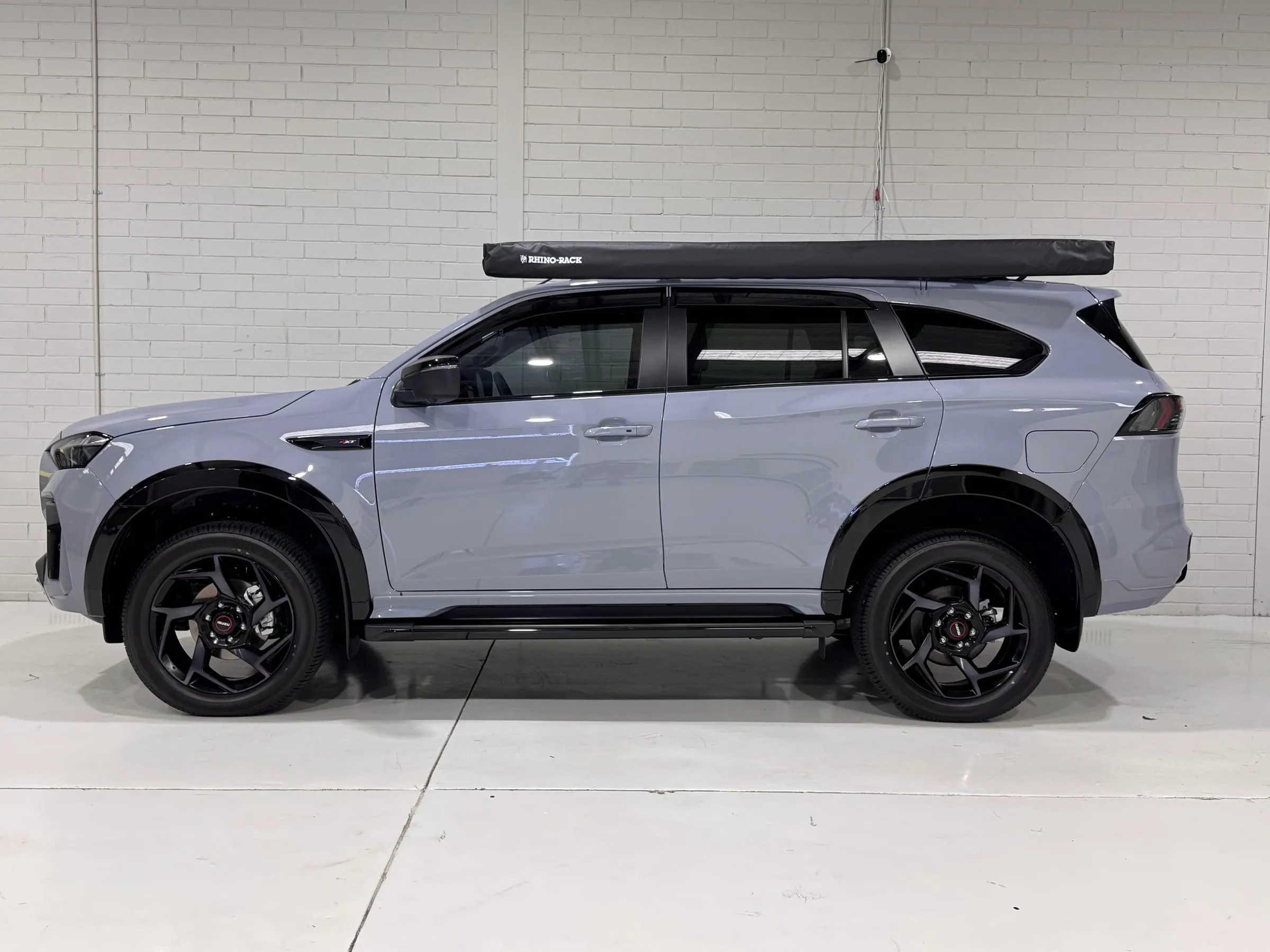 Grey Isuzu MU-X with clear paint protection film, rooftop awning and side steps, side profile in the Vinyl Wrapz workshop