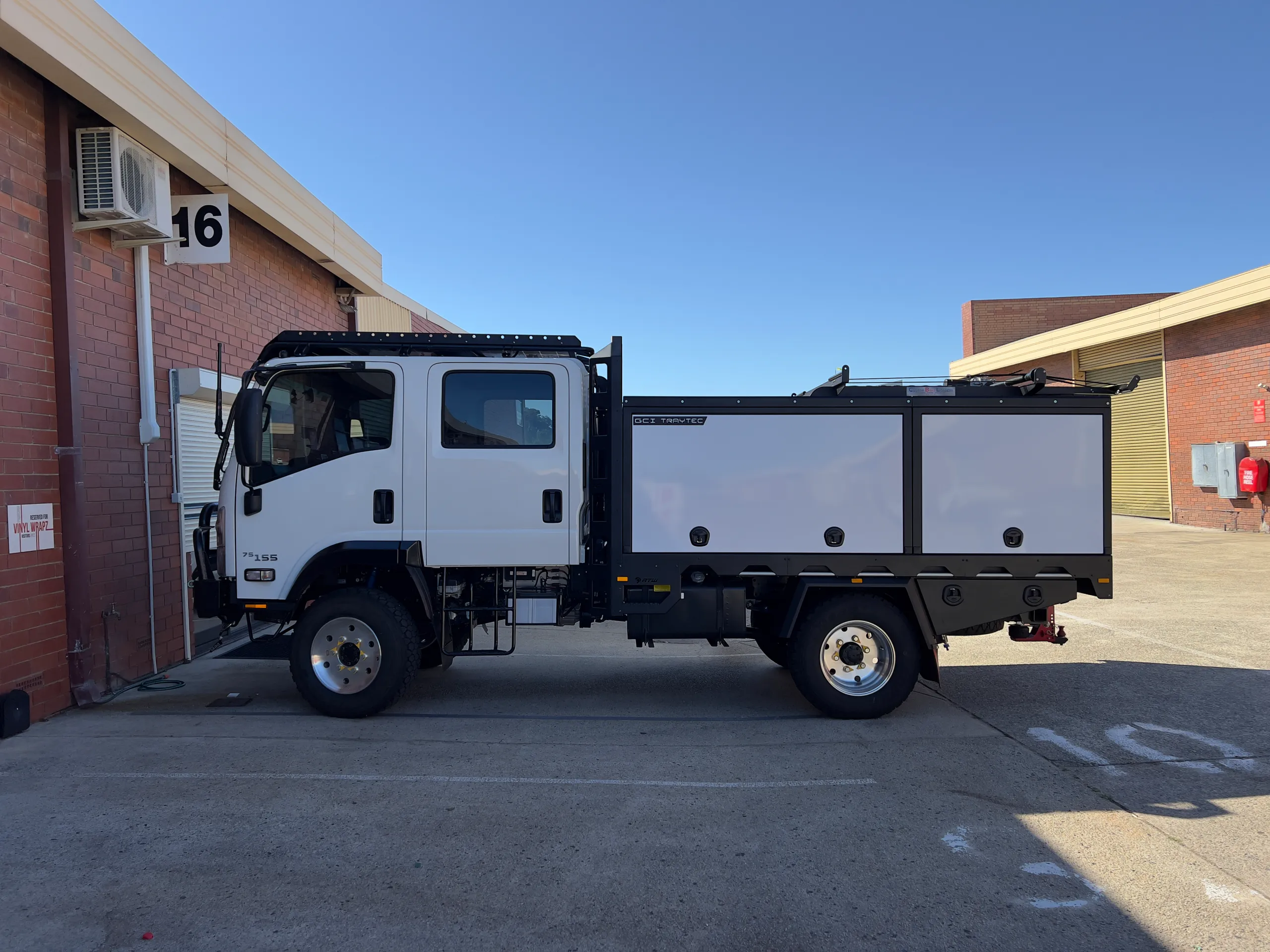Plain Isuzu camper truck parked outside before wrapping