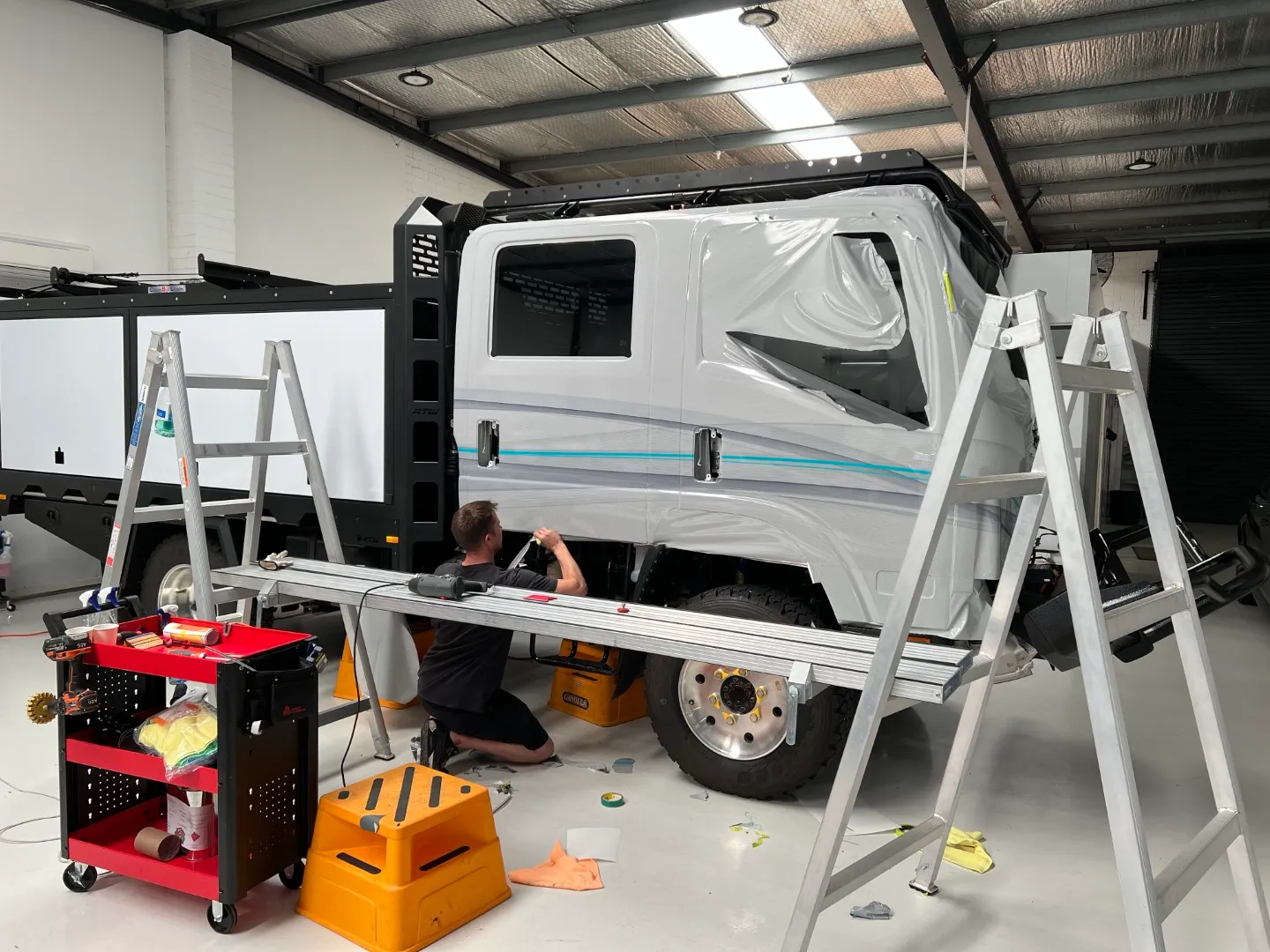 Installer kneeling beside the Isuzu cab while fitting film