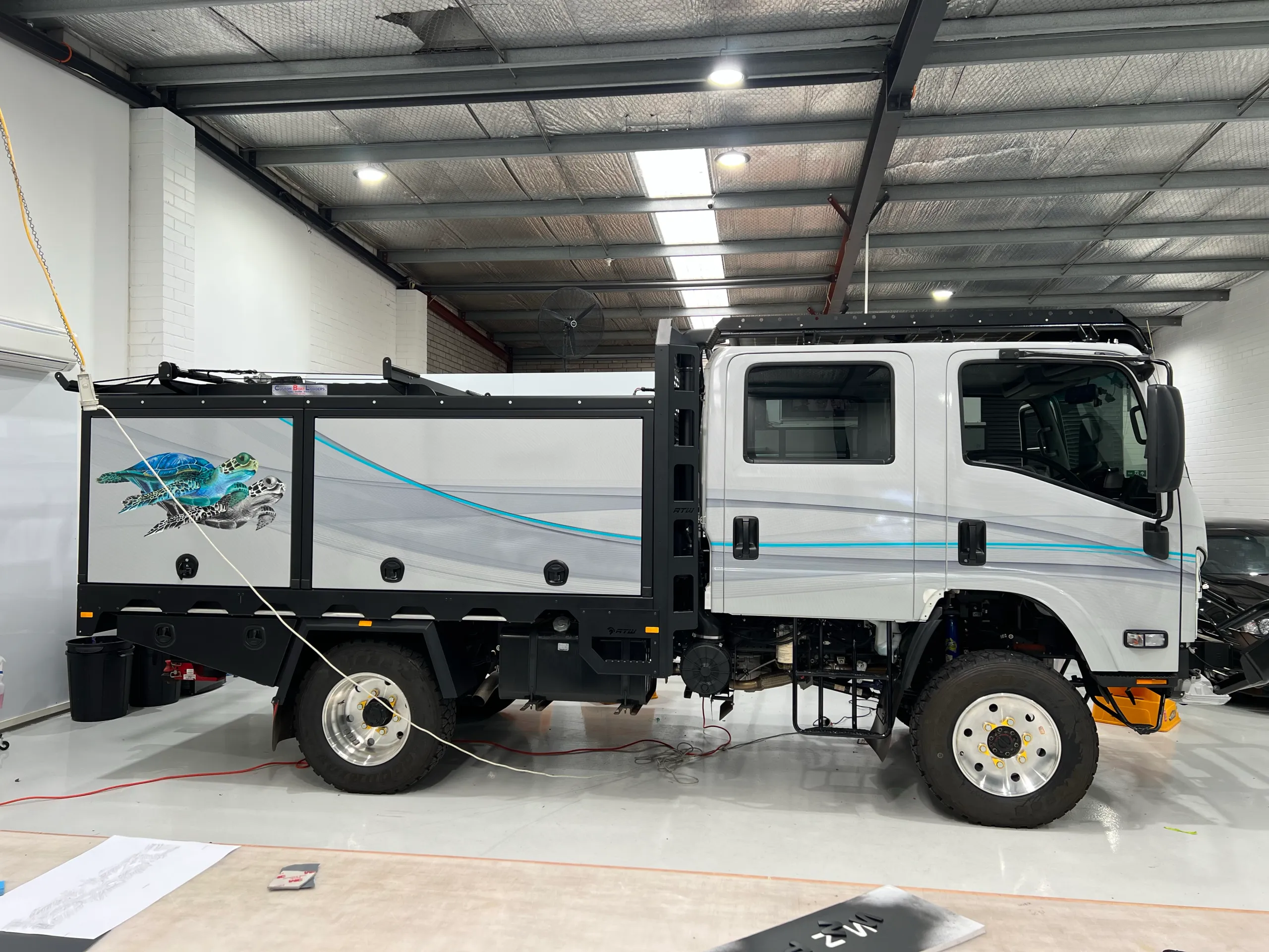 Wrapped grey camper truck showing its turtle graphic