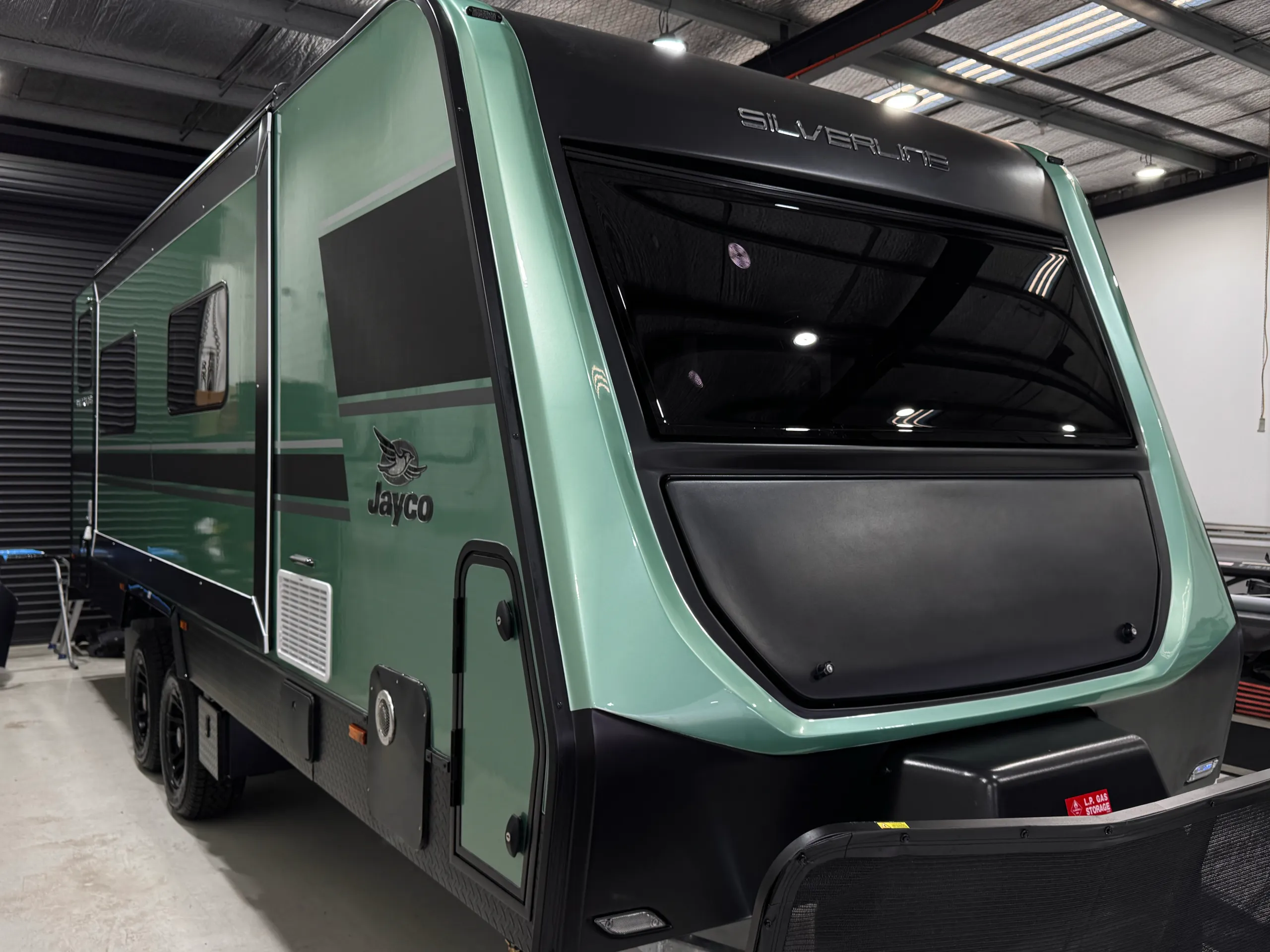 Close front-quarter view of the green Jayco Silverline caravan and black side graphics