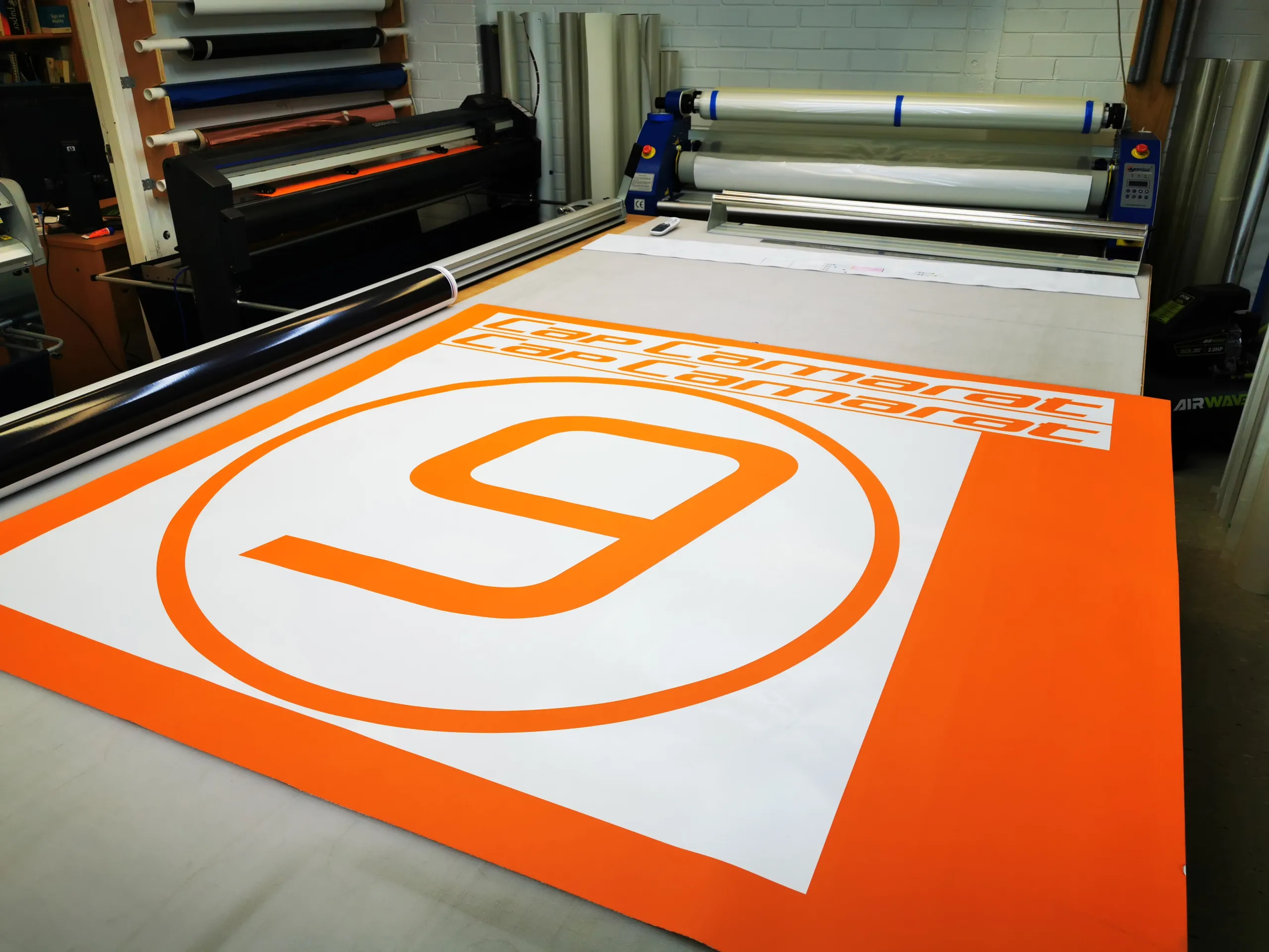 Orange Cap Camarat lettering and a number 9 graphic prepared beside workshop equipment