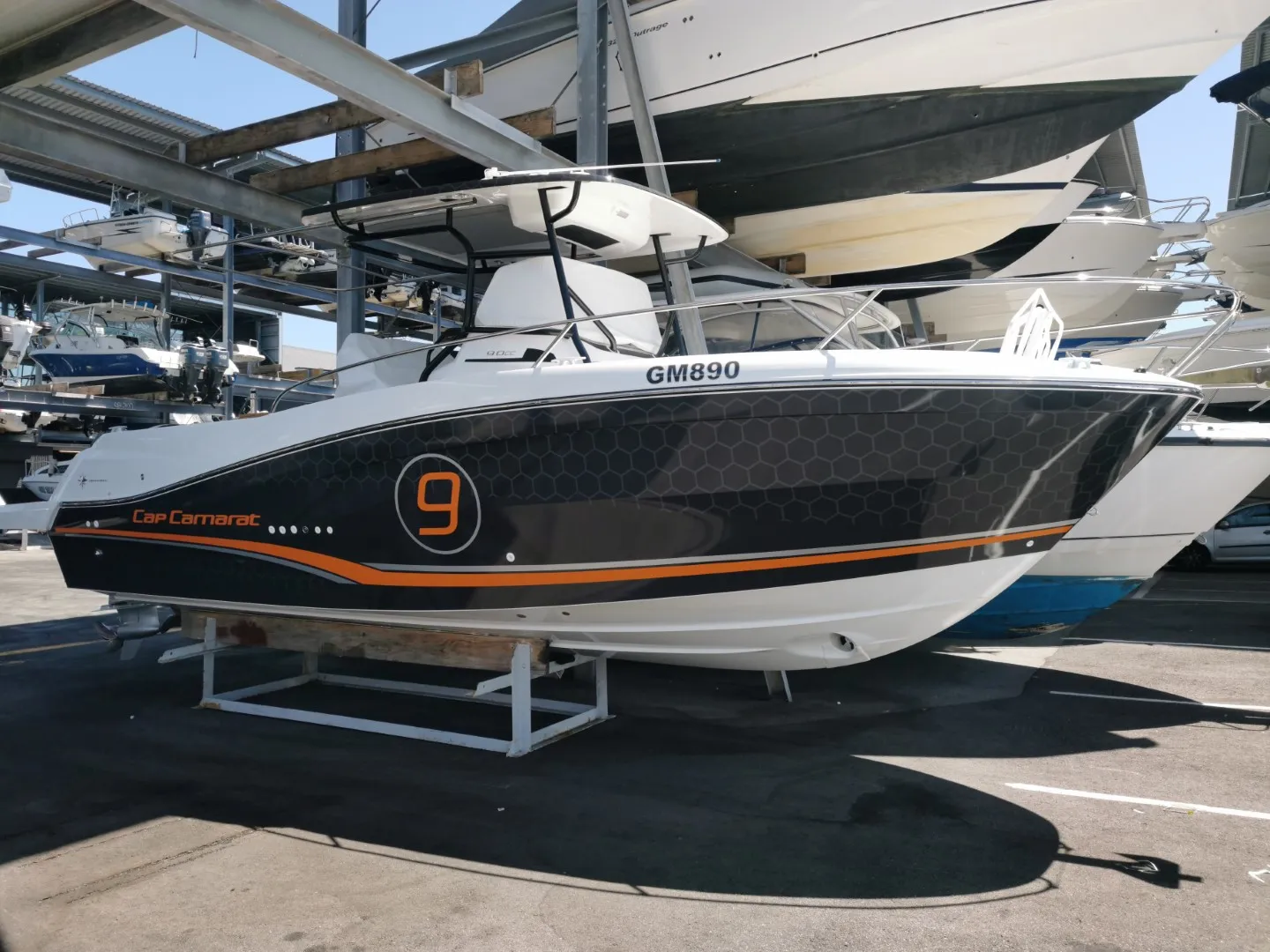 Jeanneau Cap Camarat 9 with charcoal honeycomb graphics and orange accents at the boat yard