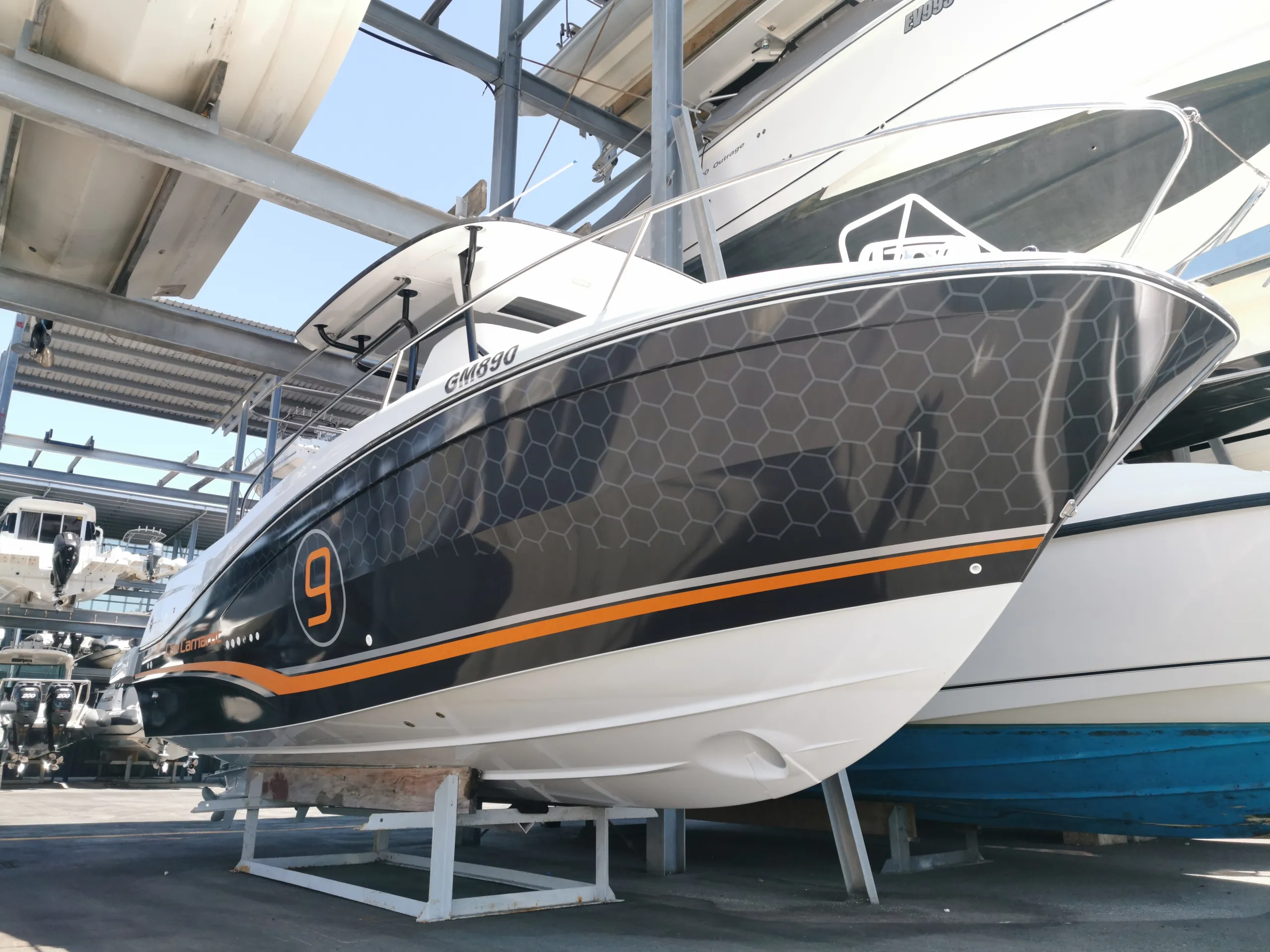 Low bow-quarter view of the Cap Camarat honeycomb wrap and orange stripe