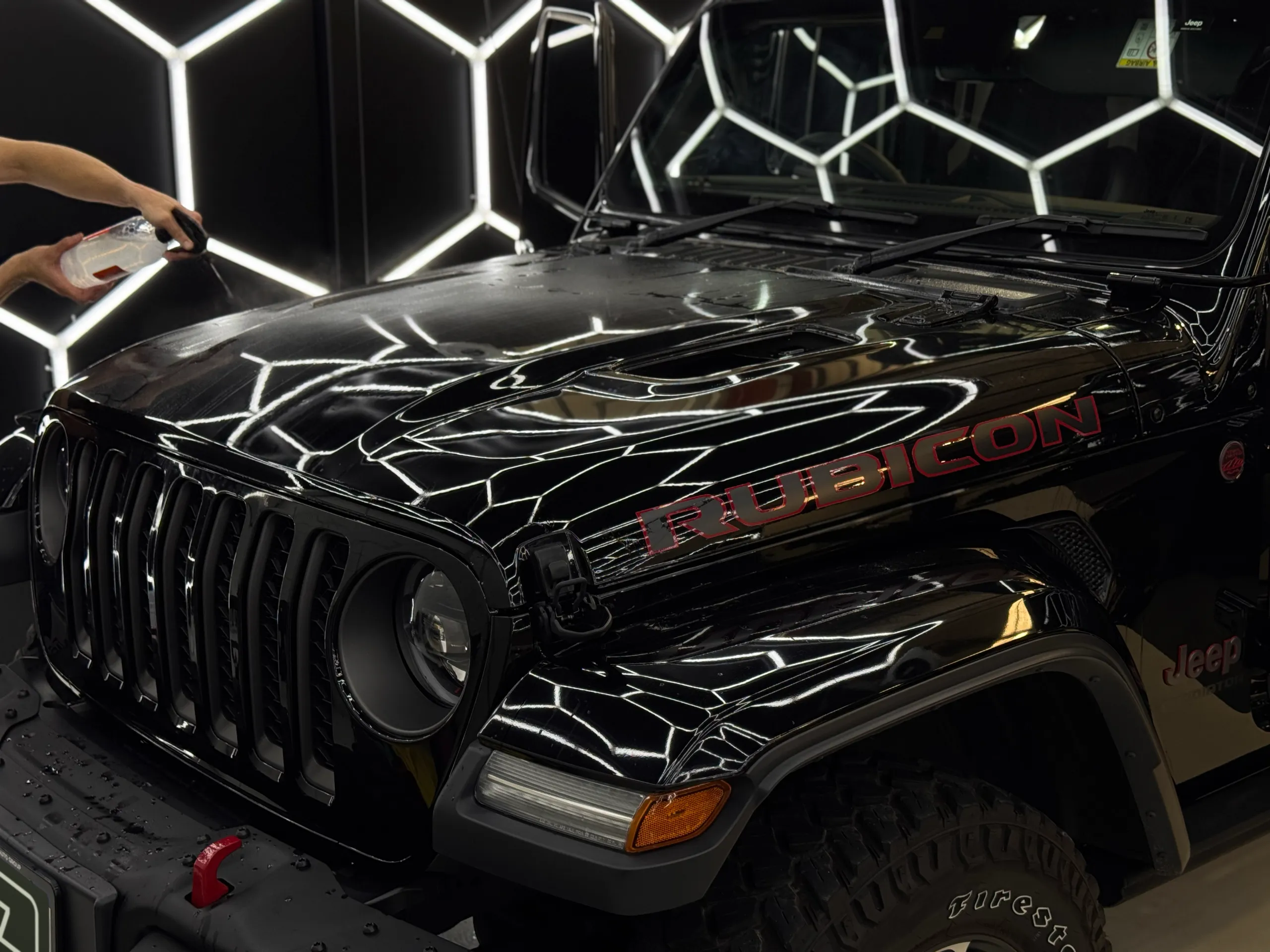 Installer spraying the Jeep Gladiator Rubicon bonnet while film is being fitted