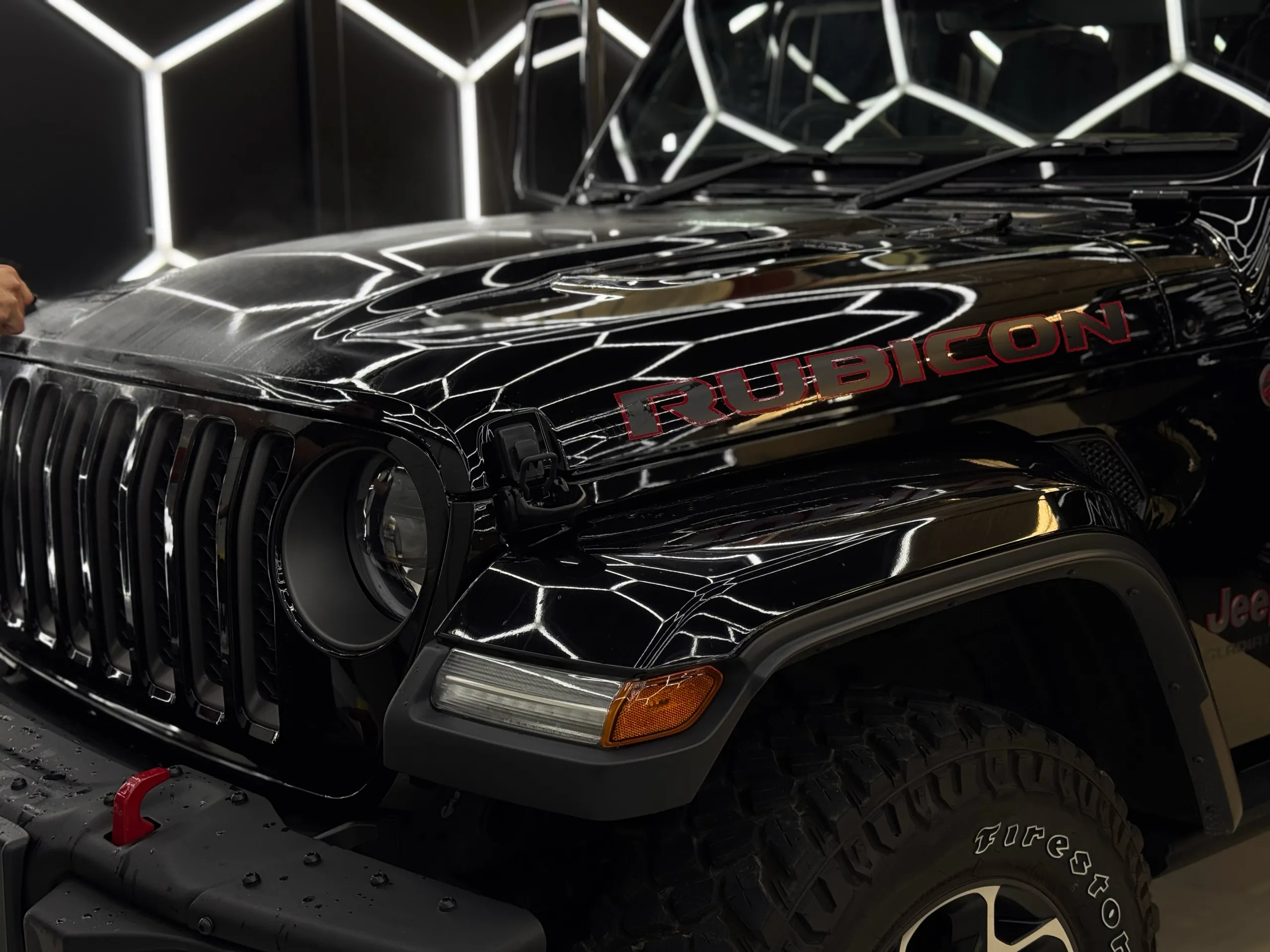 Installer fitting film across the glossy Jeep Gladiator Rubicon bonnet