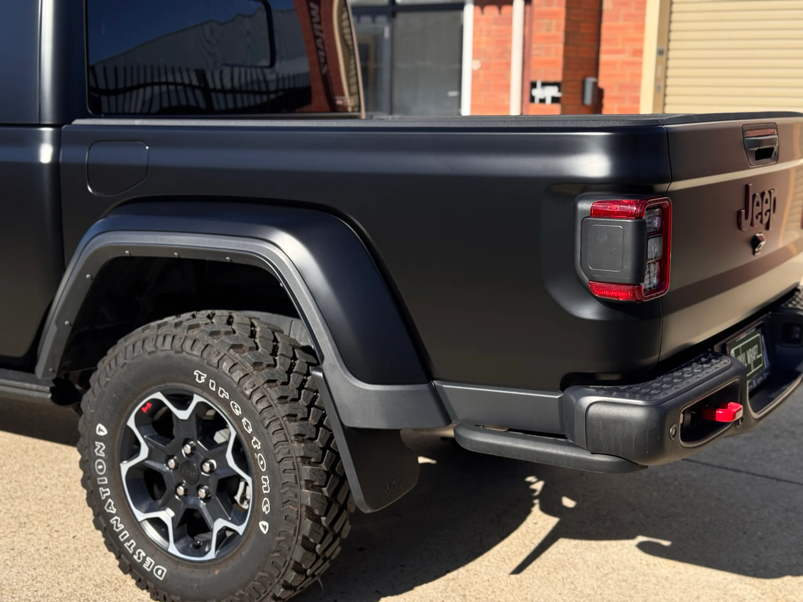 Matte black Jeep Gladiator Rubicon tailgate, tray side and rear wheel outdoors