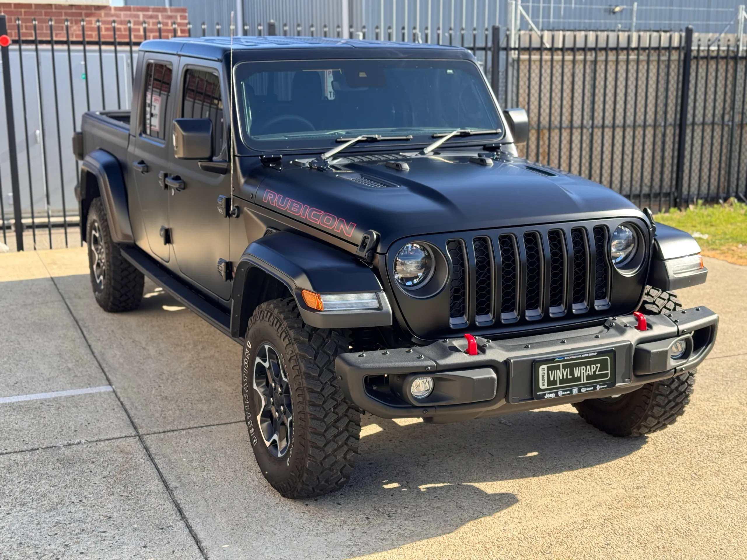 Matte black Jeep Gladiator Rubicon parked outside by a fence
