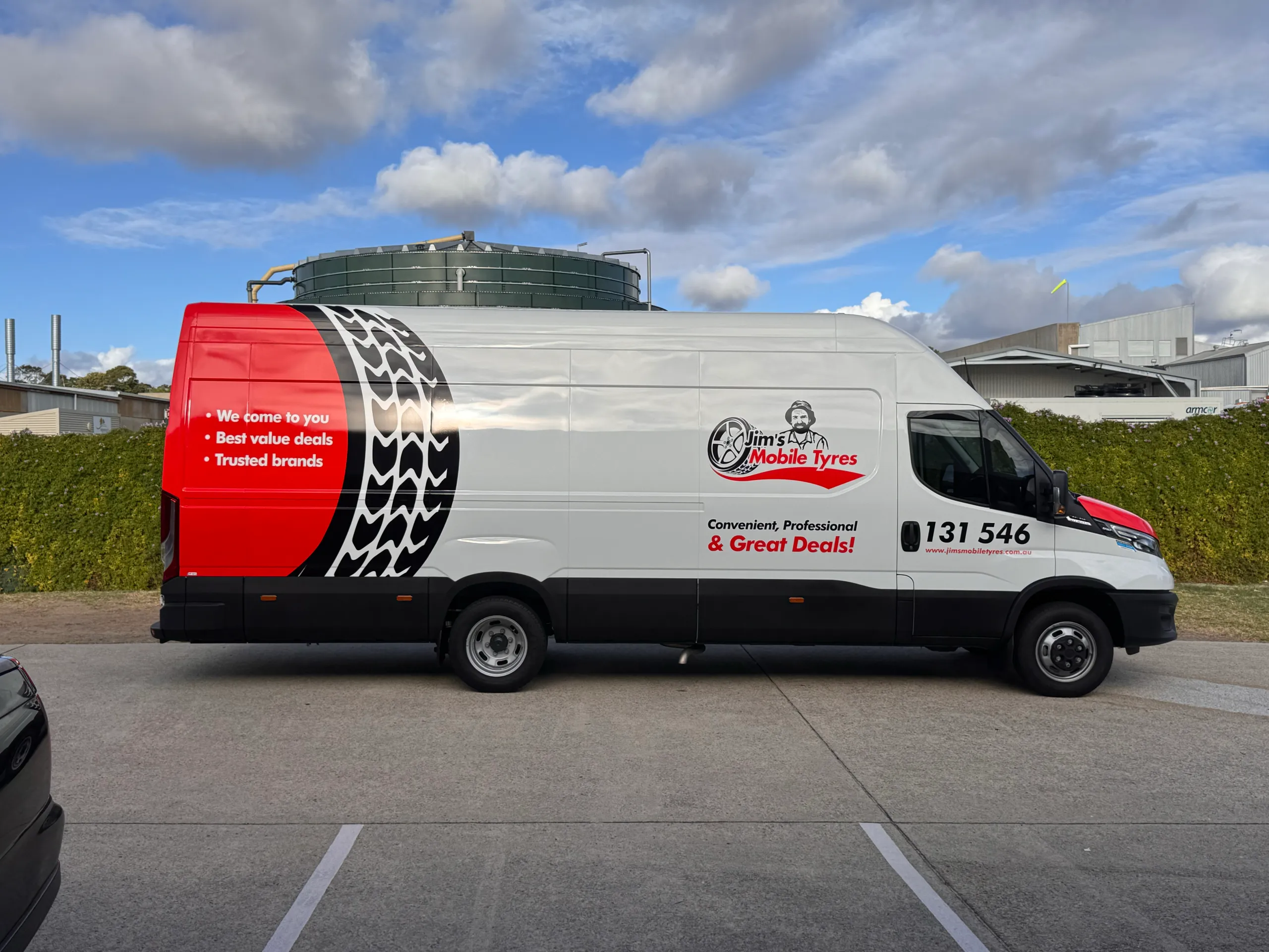 Side profile of the Jim's Mobile Tyres van with a red rear panel and black tyre-tread stripe
