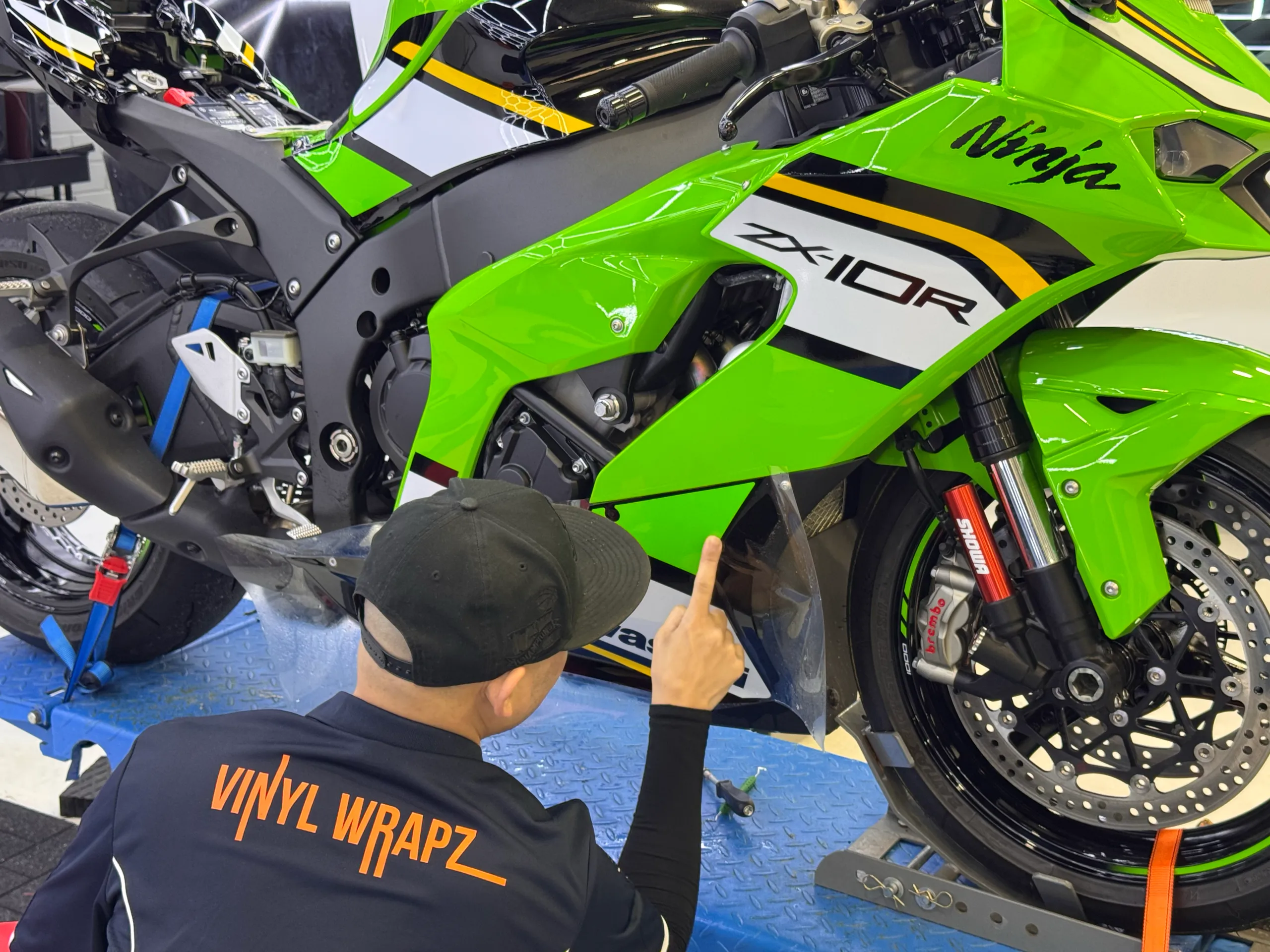 Installer fitting clear film around the green Kawasaki Ninja ZX-10R fairing