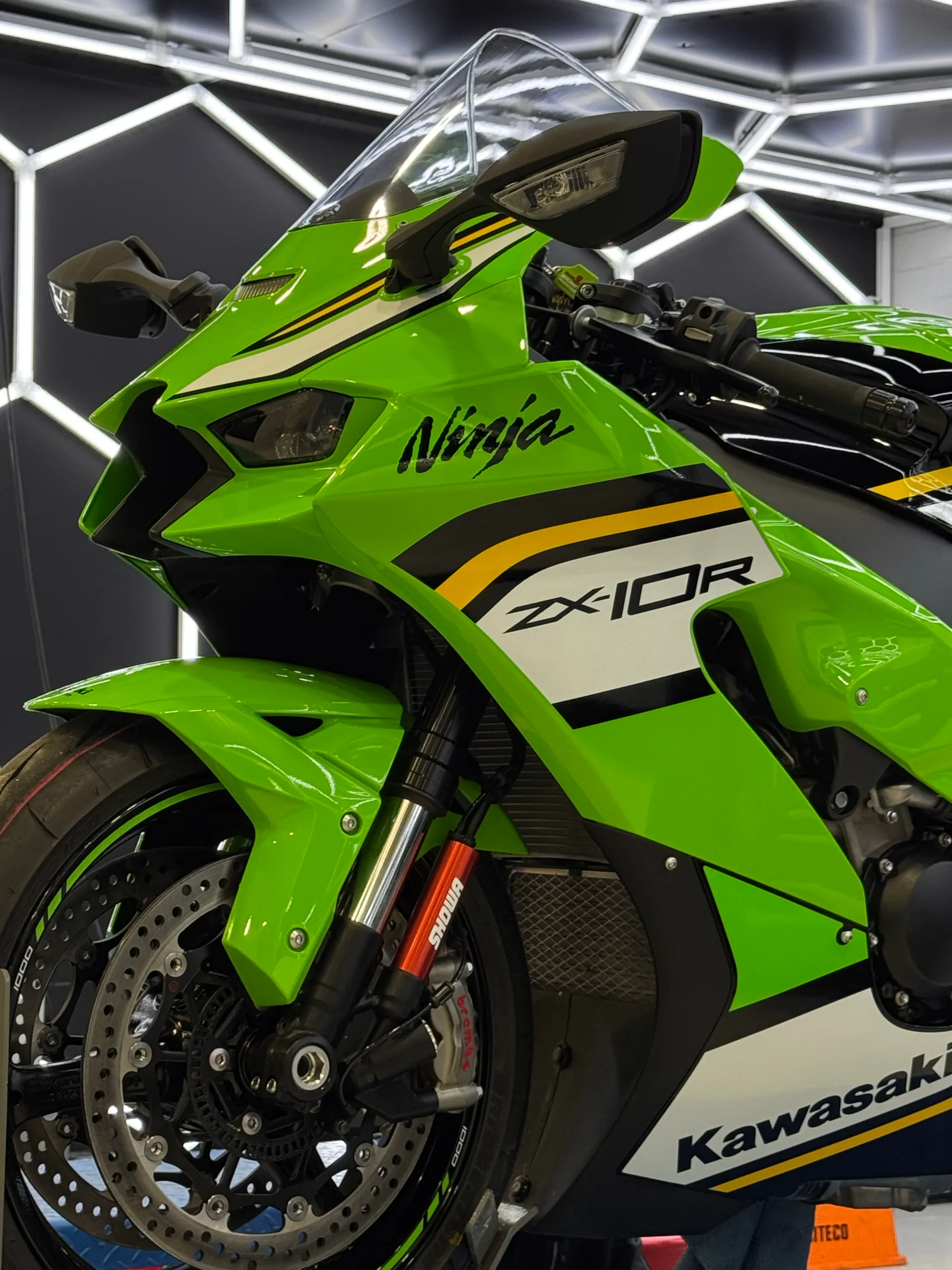 Kawasaki Ninja ZX-10R green fairing and front wheel beneath workshop lights