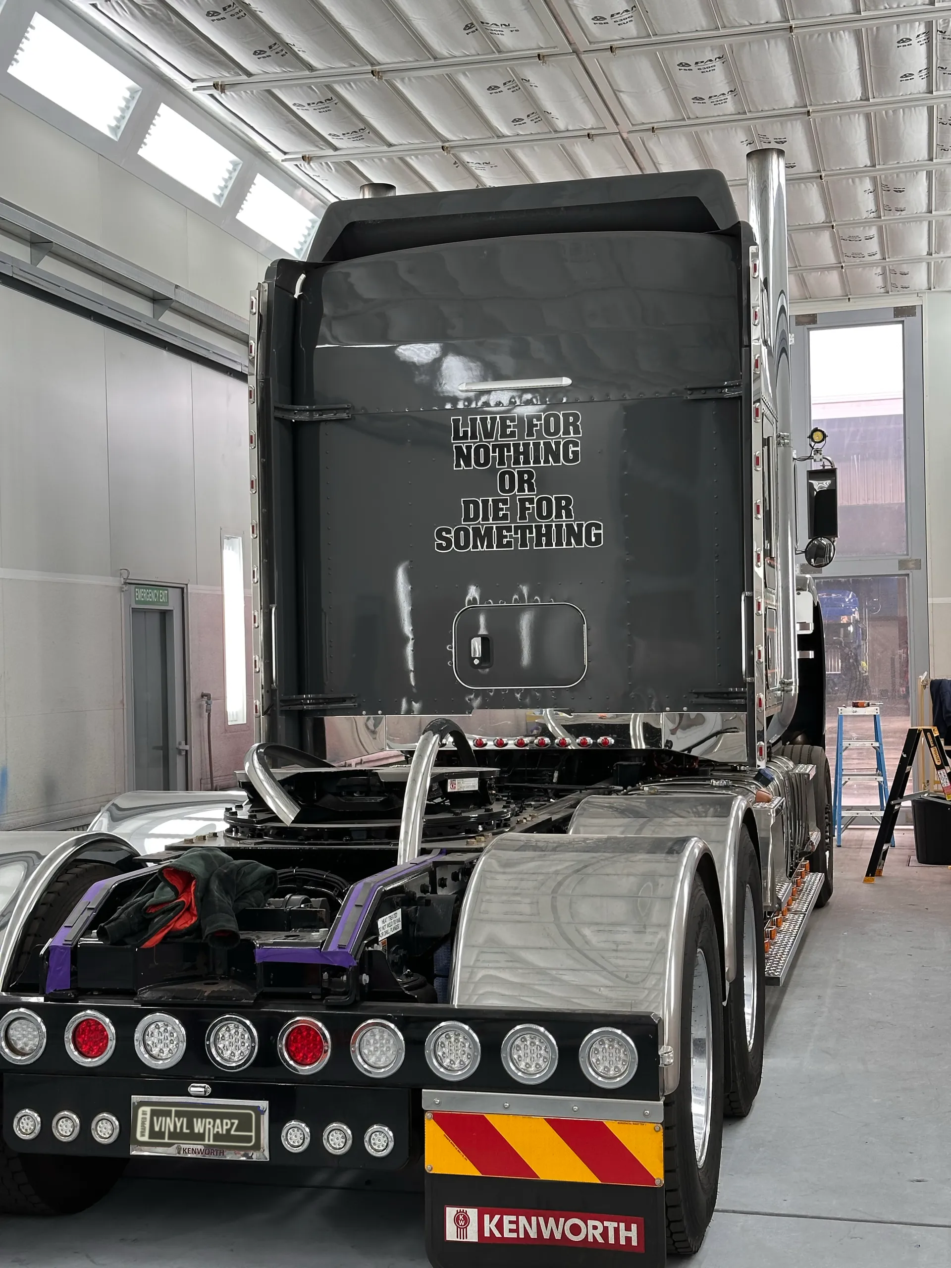 Rear view of the grey Kenworth cab, chassis and rear lights inside the workshop