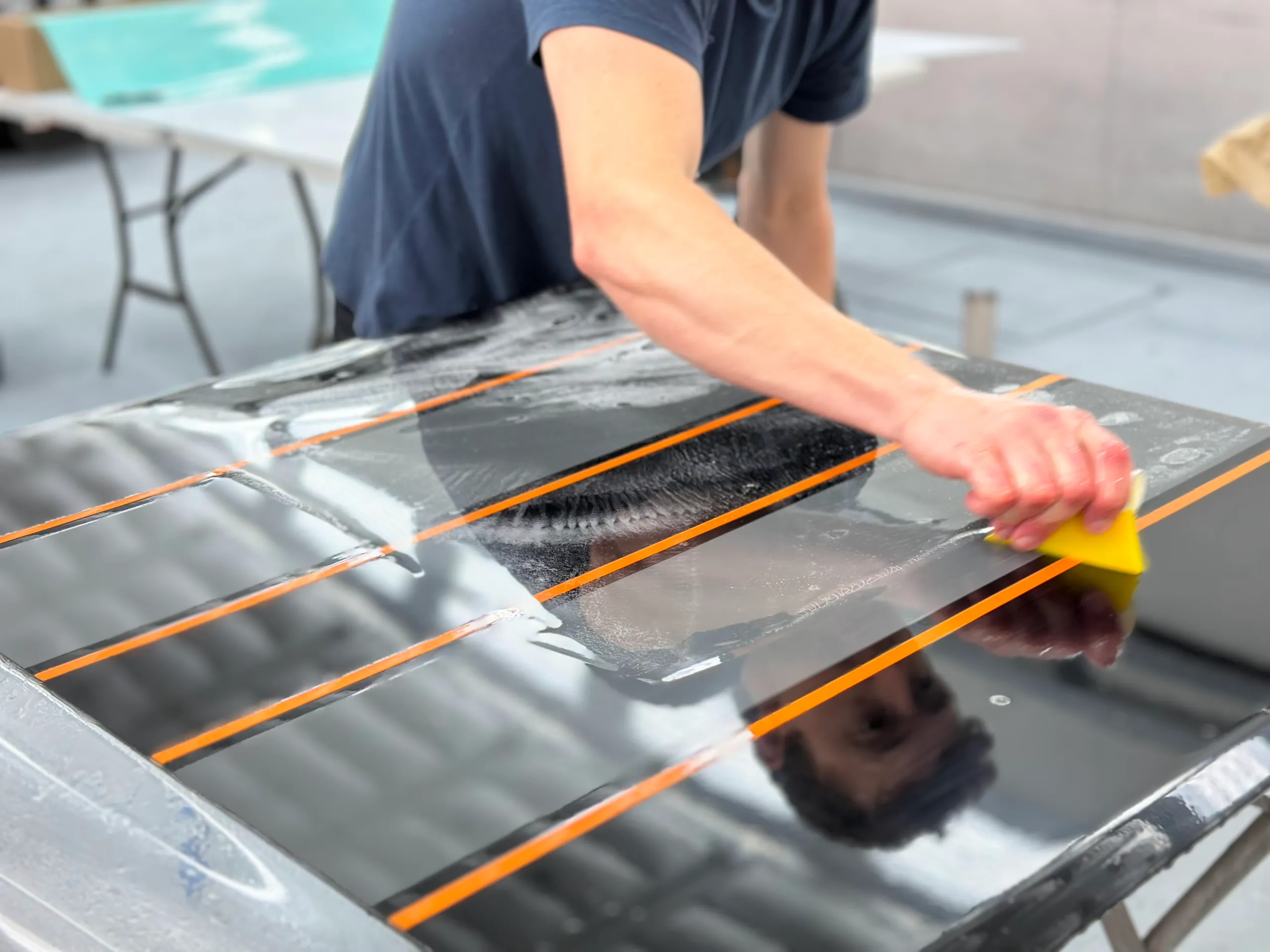 Installer using a yellow squeegee on clear film over a striped truck panel