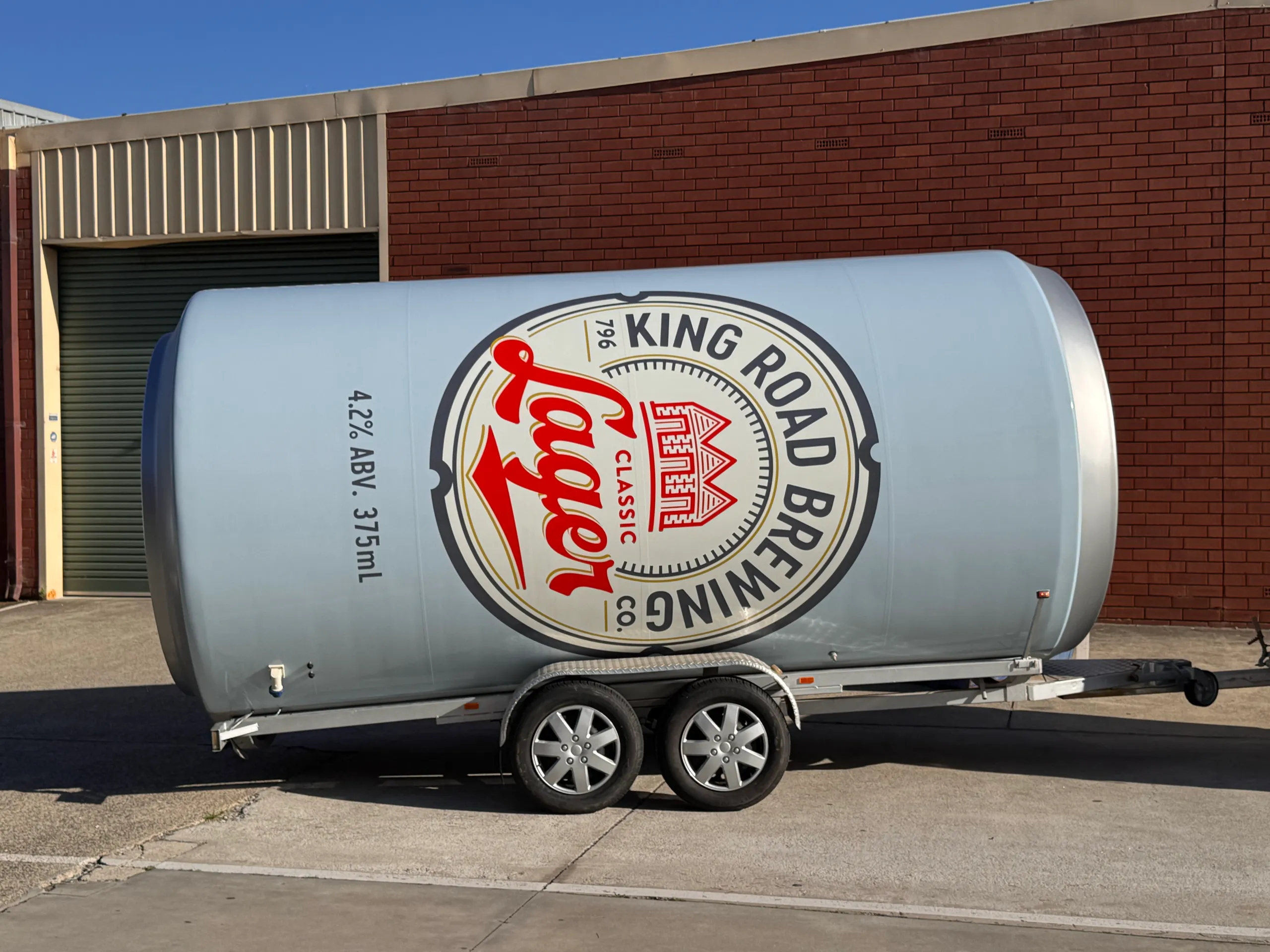 King Road Lager can-shaped trailer in side profile outside the workshop