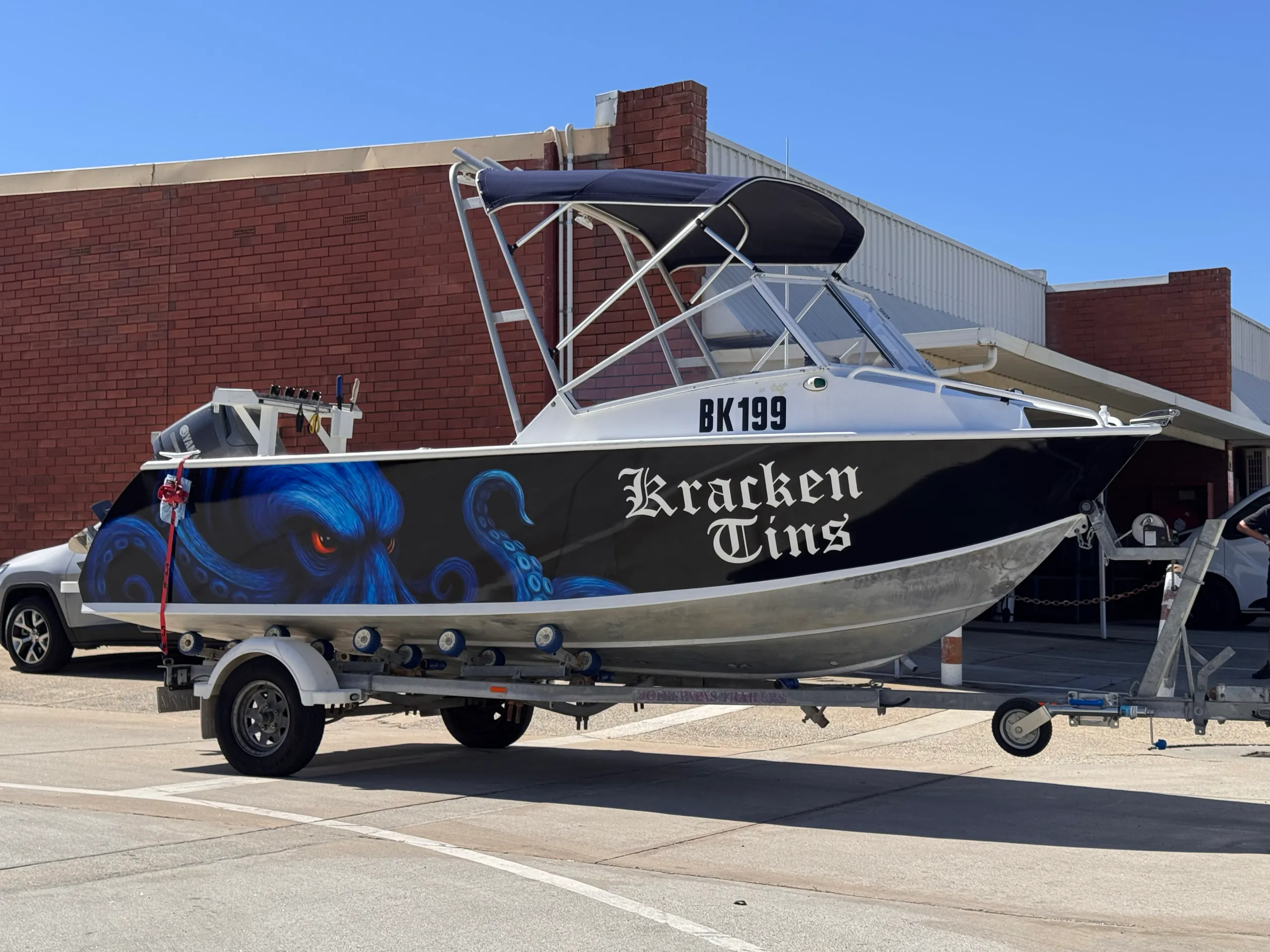 Kracken Tins blue and black hull graphics on a boat parked outside on its trailer