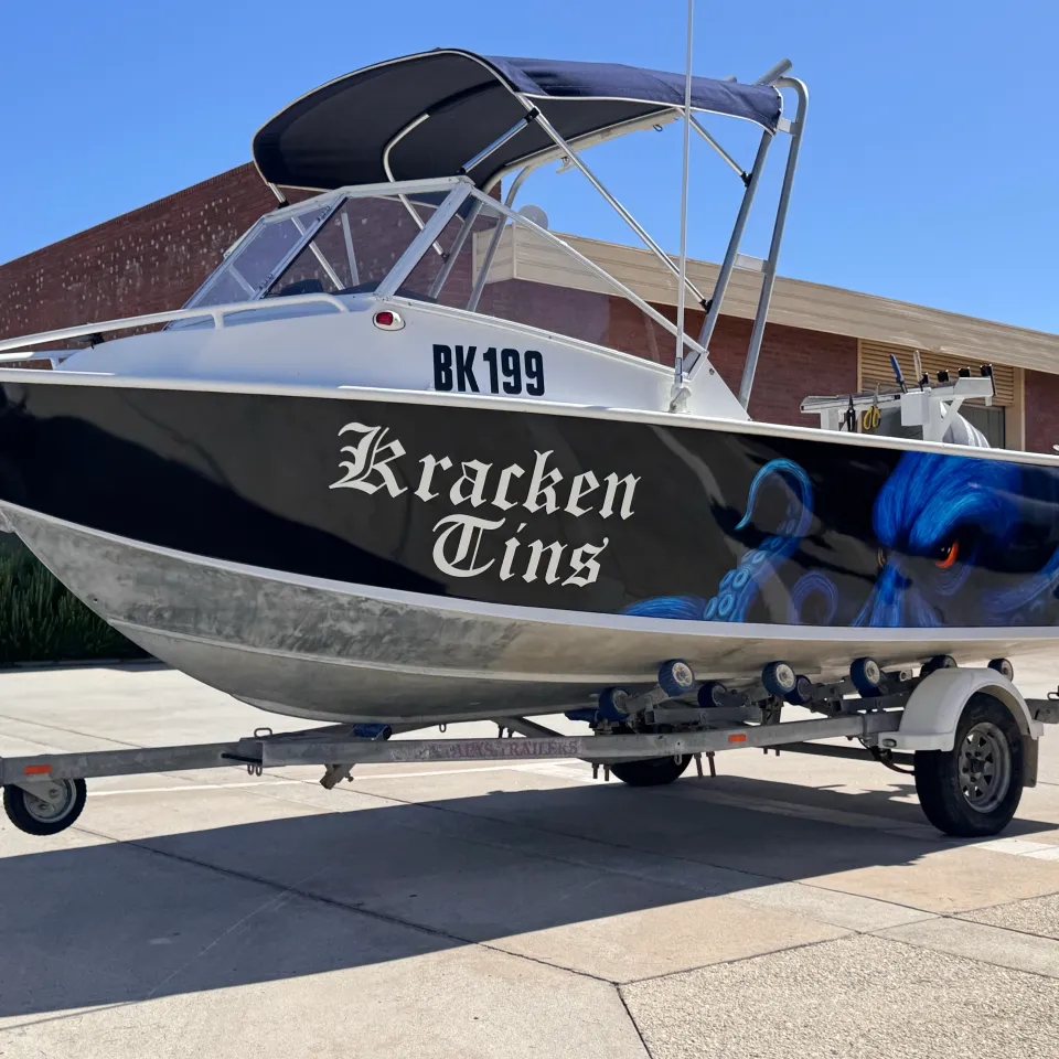 Bow-quarter view of the Kracken Tins boat with blue octopus artwork on a black hull