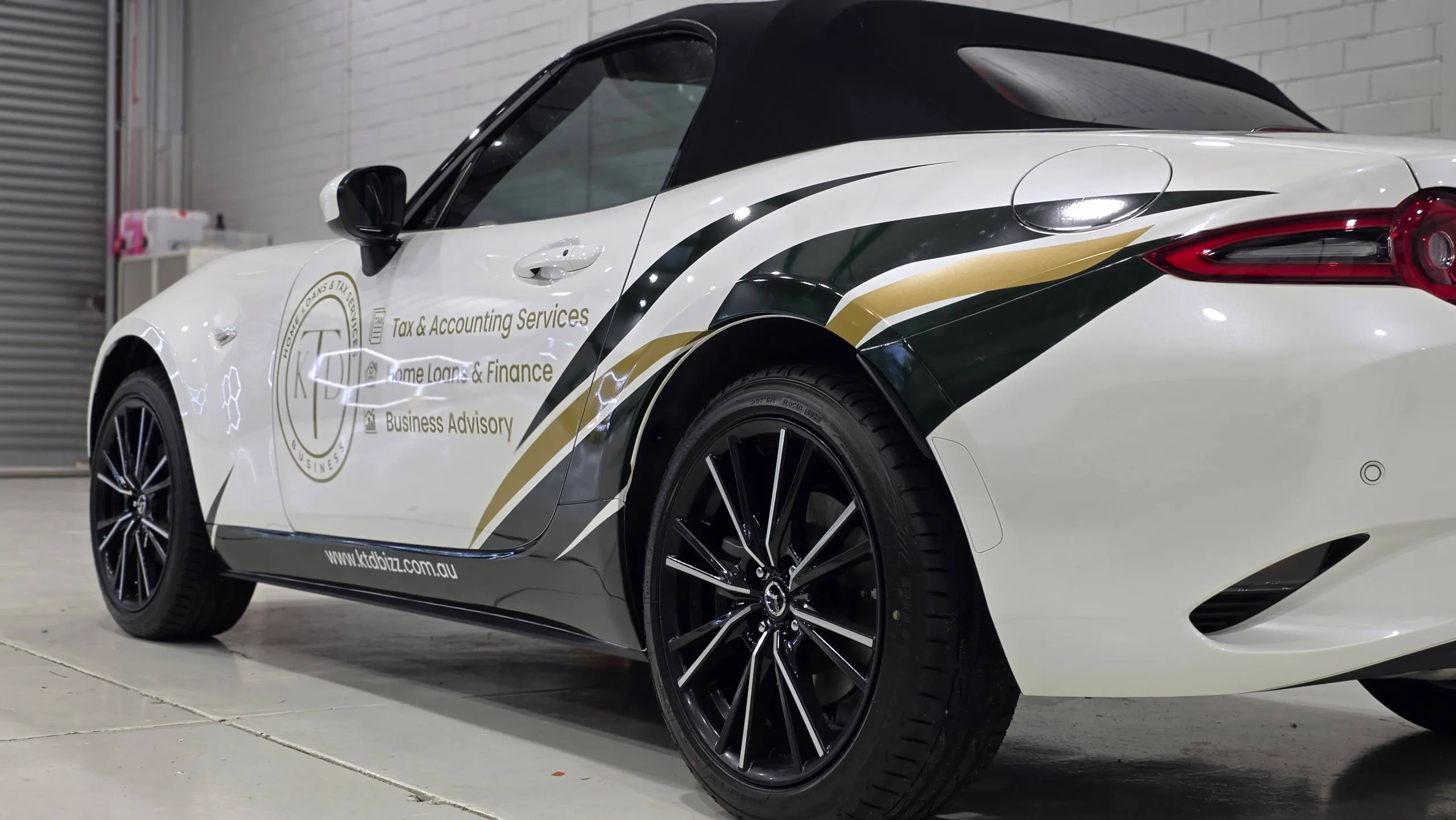 Green and gold KTD graphics along the white Mazda MX-5 door and rear quarter