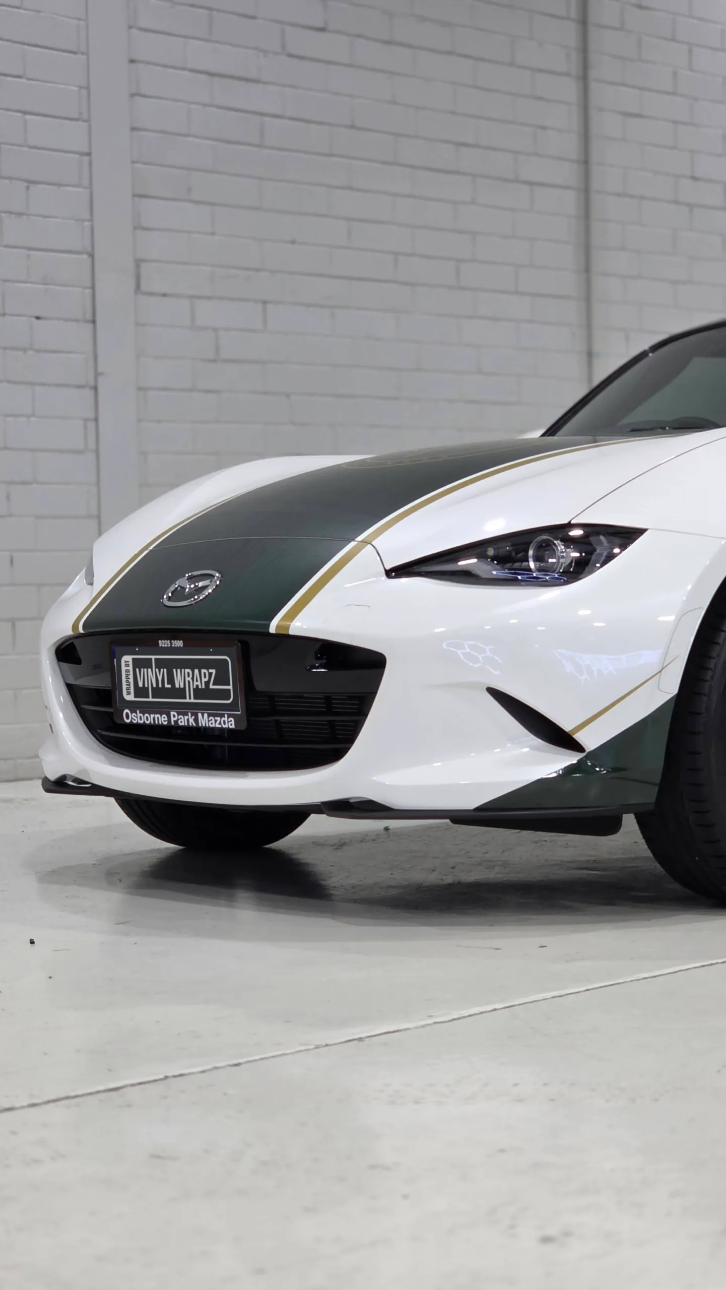White Mazda MX-5 front corner with a green and gold bonnet stripe