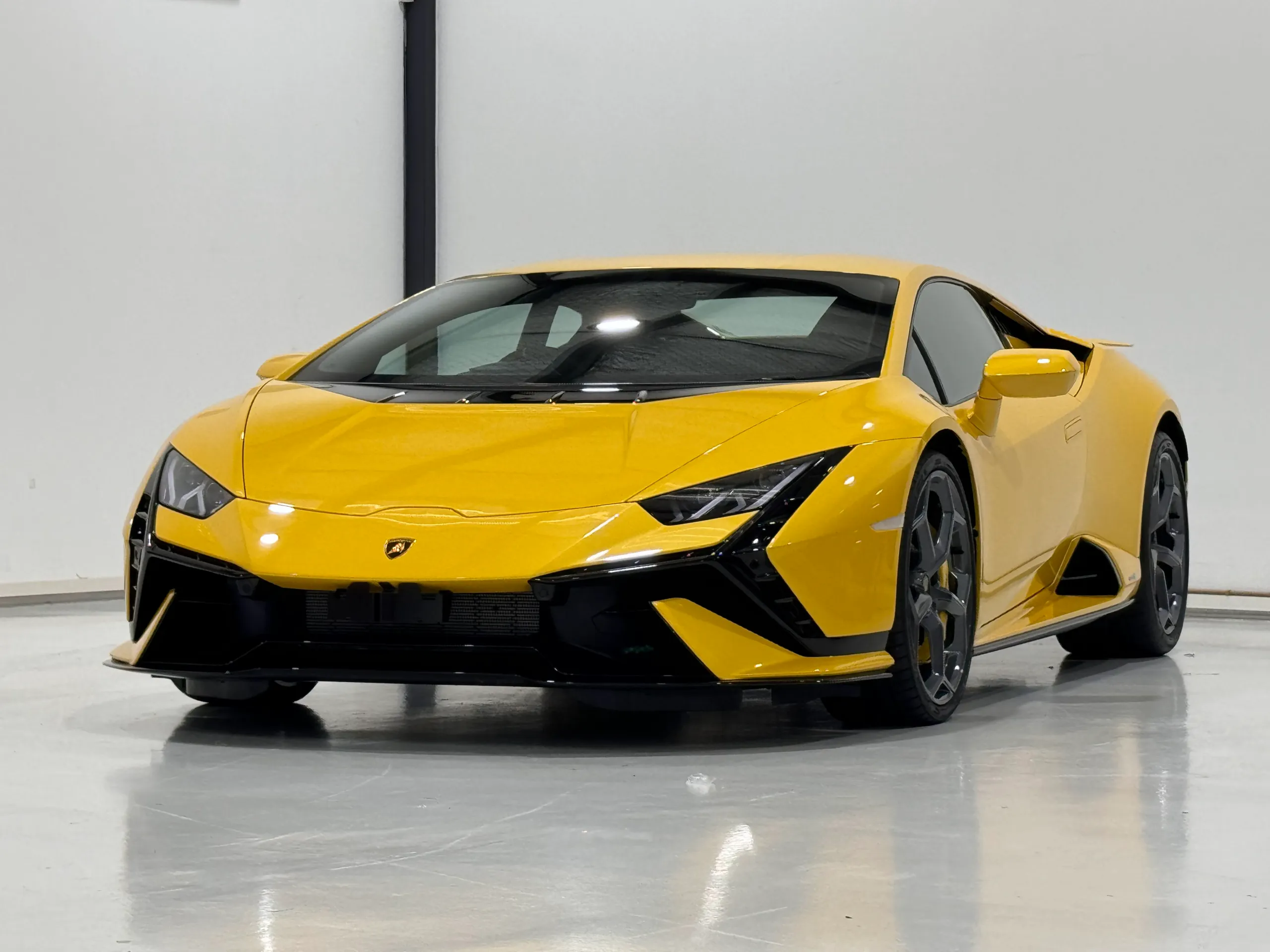 Yellow Lamborghini Huracan Tecnica against a plain workshop wall
