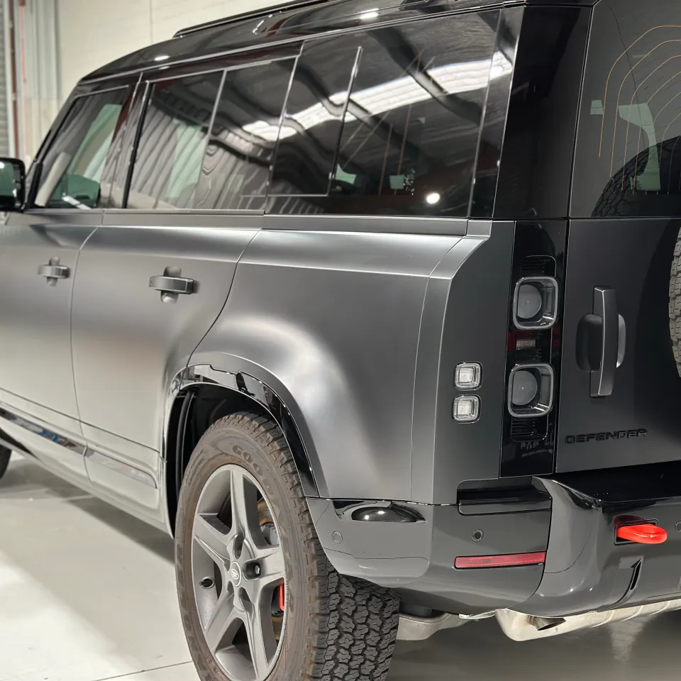 Land Rover Defender rear quarter showing matte grey doors, gloss black trim and its exposed spare tyre