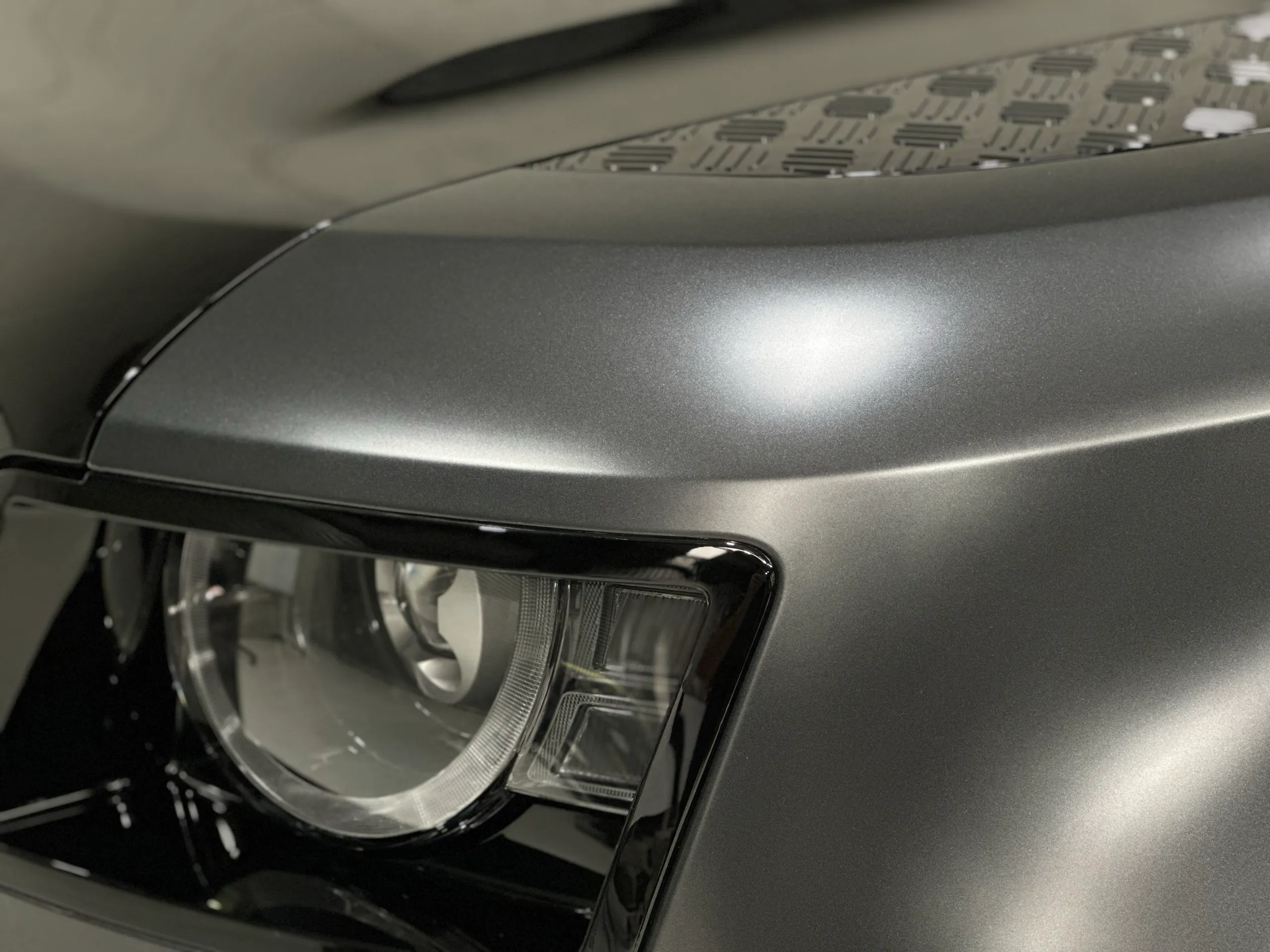 Matte grey Land Rover Defender front guard above the headlight beside a textured bonnet panel