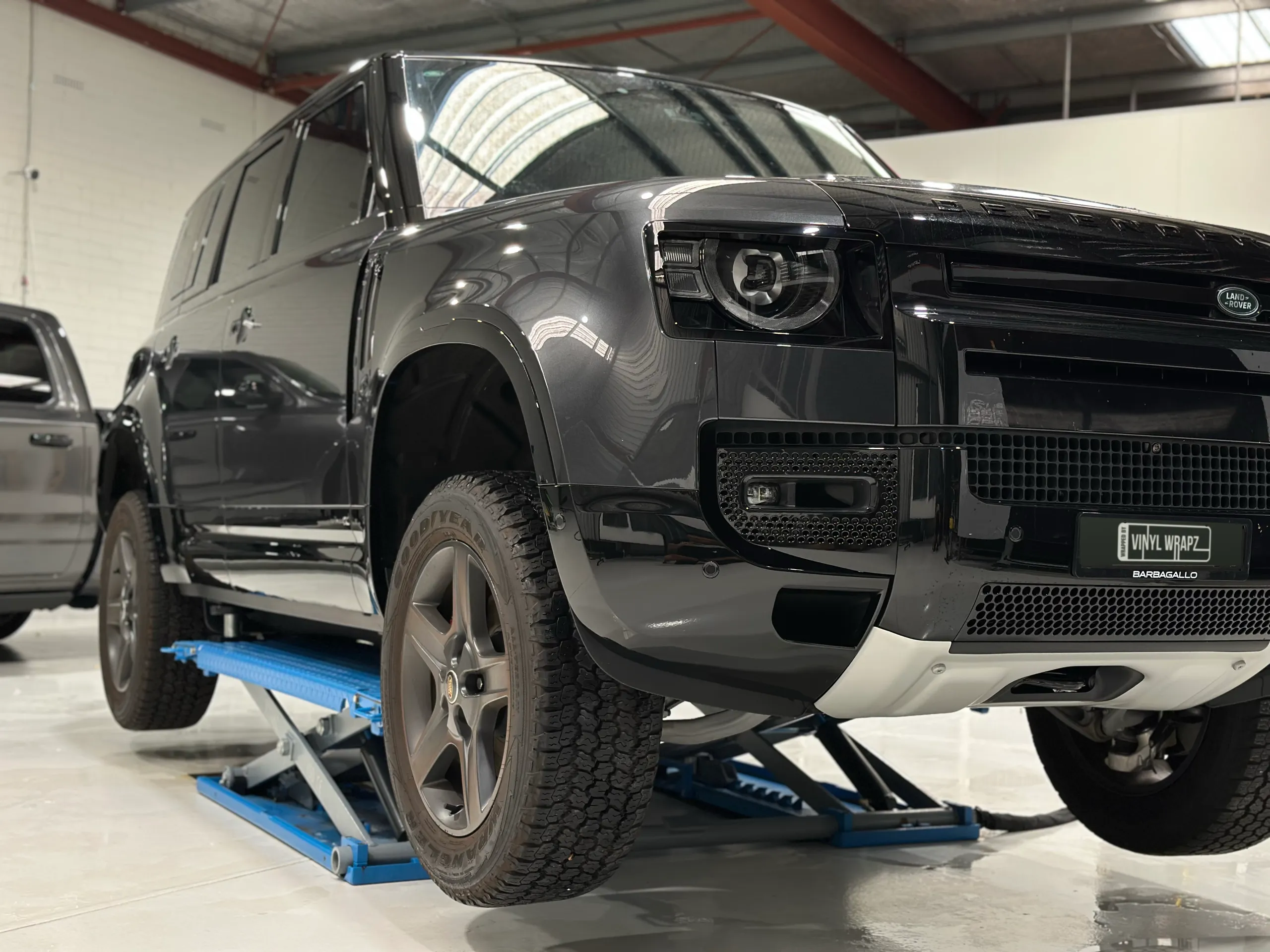 Gloss dark grey Land Rover Defender on a workshop lift before its matte-and-gloss conversion