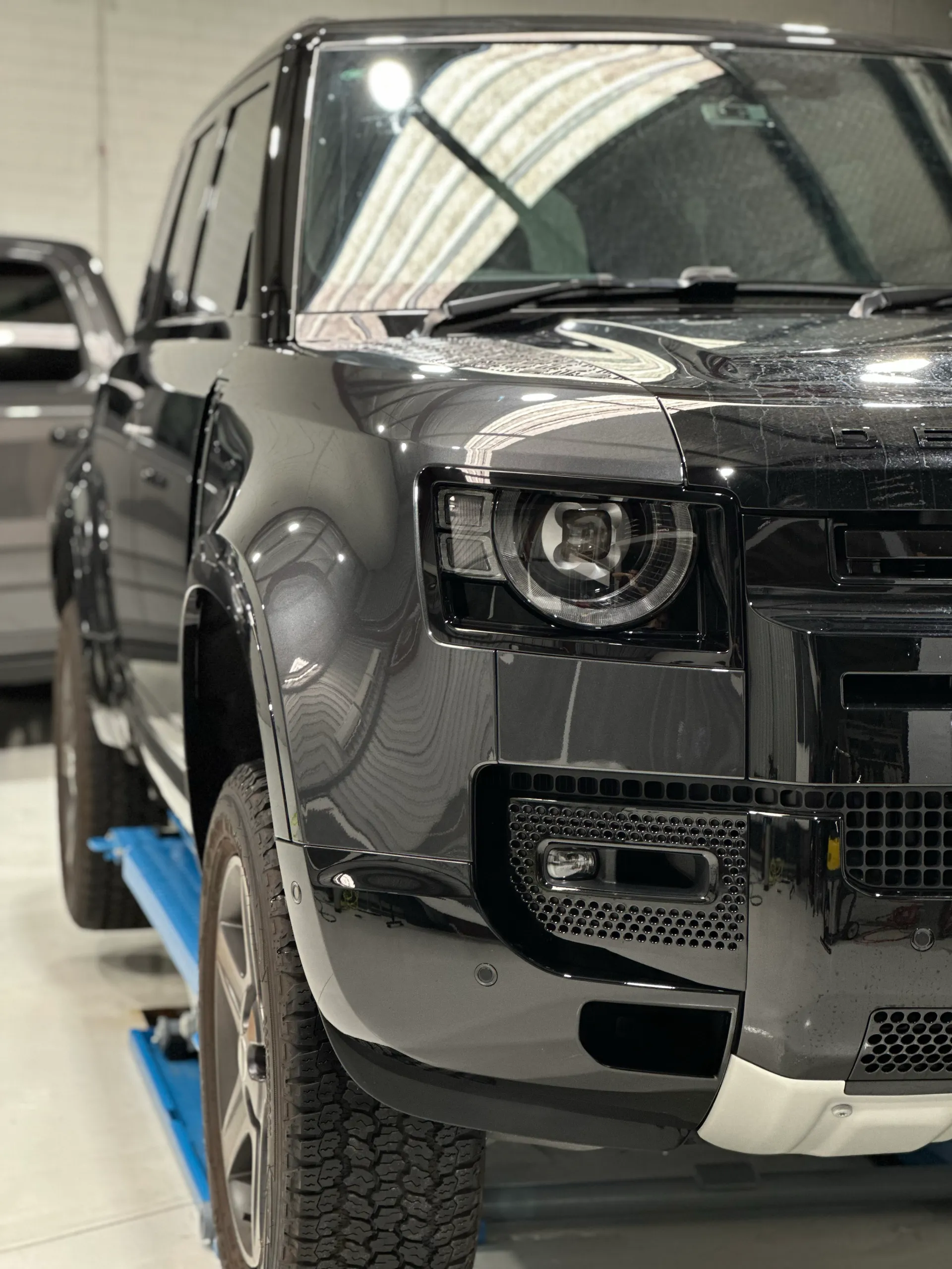 Gloss dark grey Land Rover Defender front corner on a lift before its finish conversion