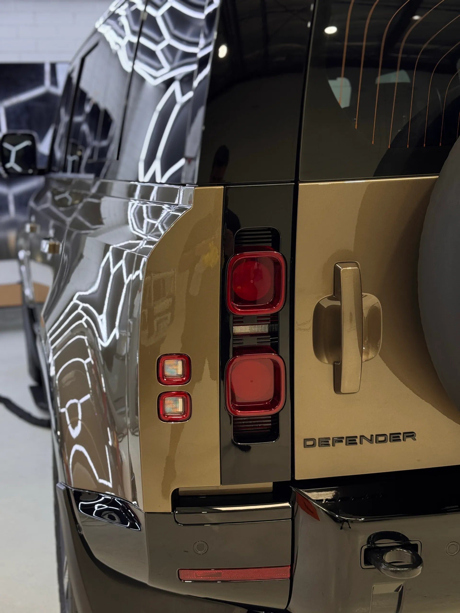 Rear lights and tailgate edge of a gloss bronze Land Rover Defender