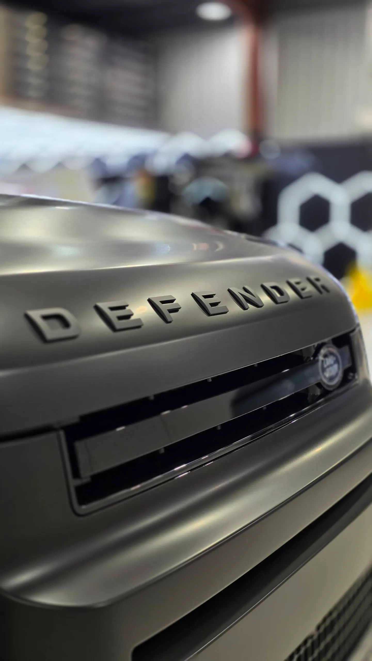 Defender lettering above the grille on a matte dark grey Land Rover bonnet