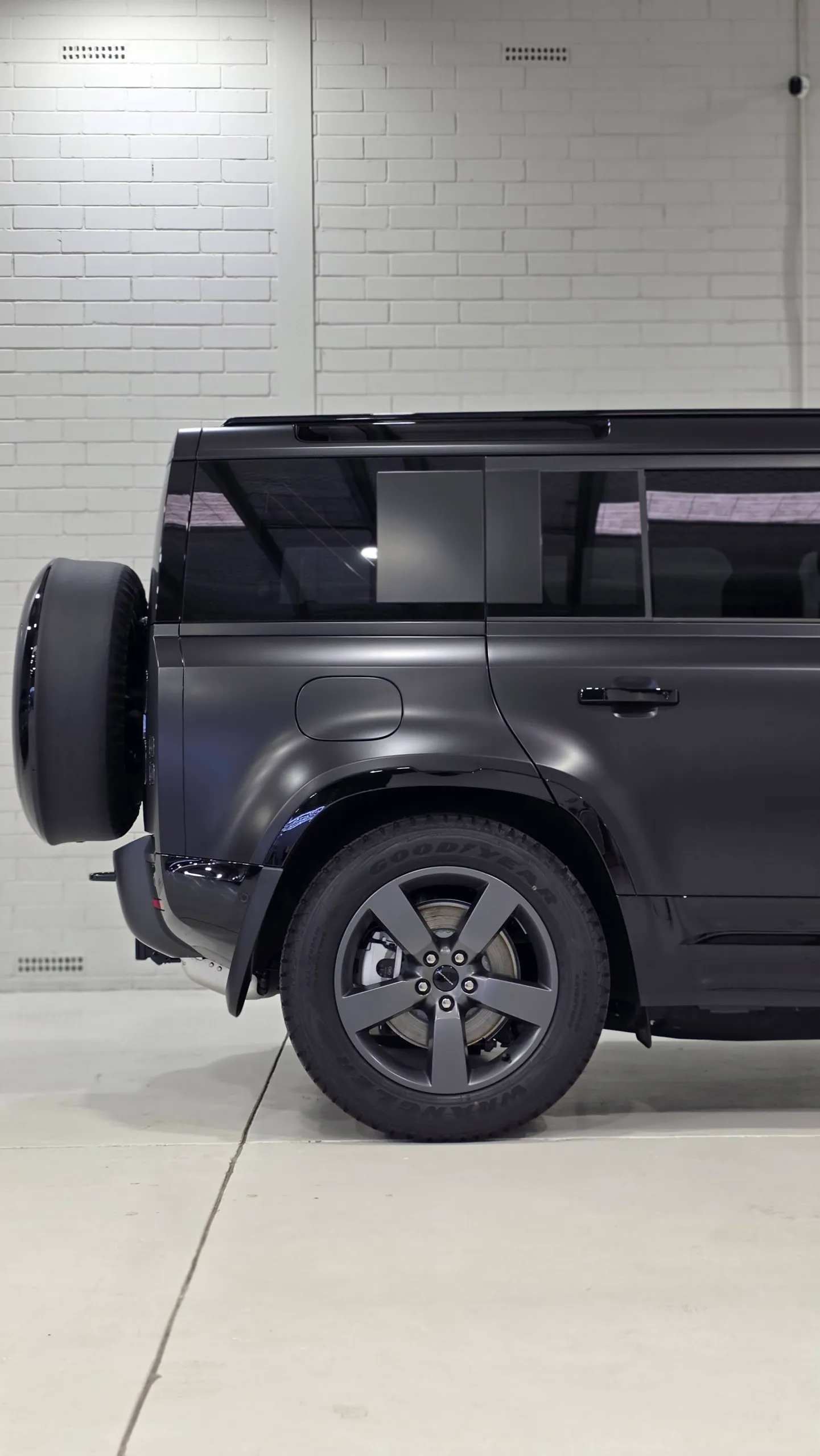Side detail of a matte dark grey Land Rover Defender rear quarter and wheel