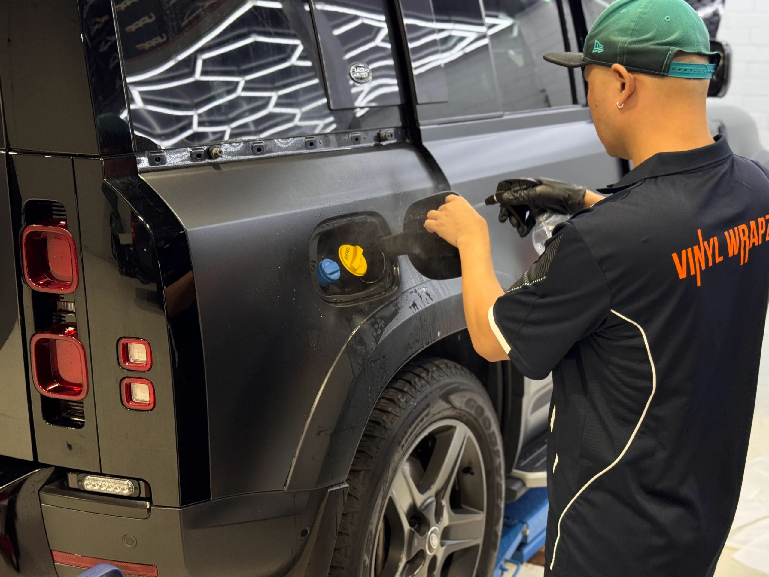 Installer fitting film around the Land Rover Defender fuel filler opening and rear wheel arch