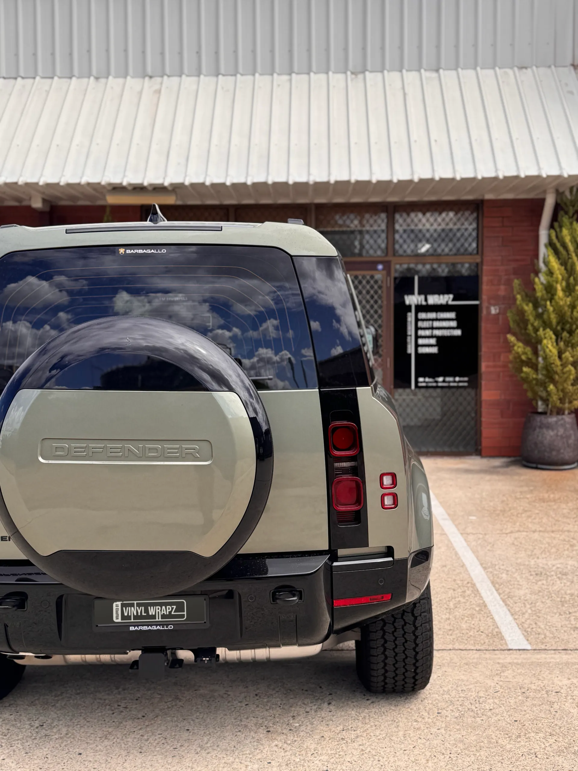 Rear view of the green Defender showing its spare wheel cover and tail lights