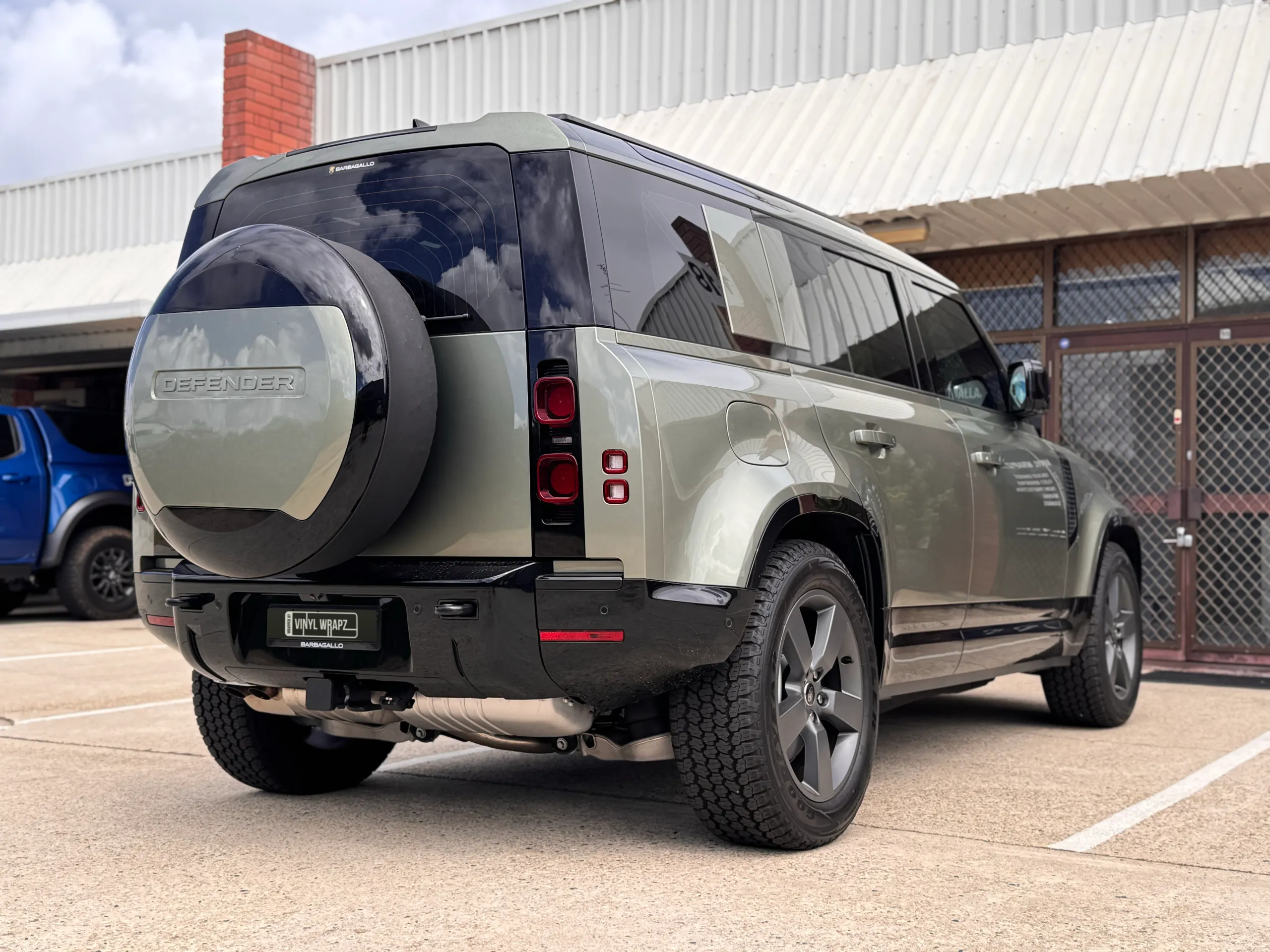 Low rear-quarter view of the green Land Rover Defender outside the workshop