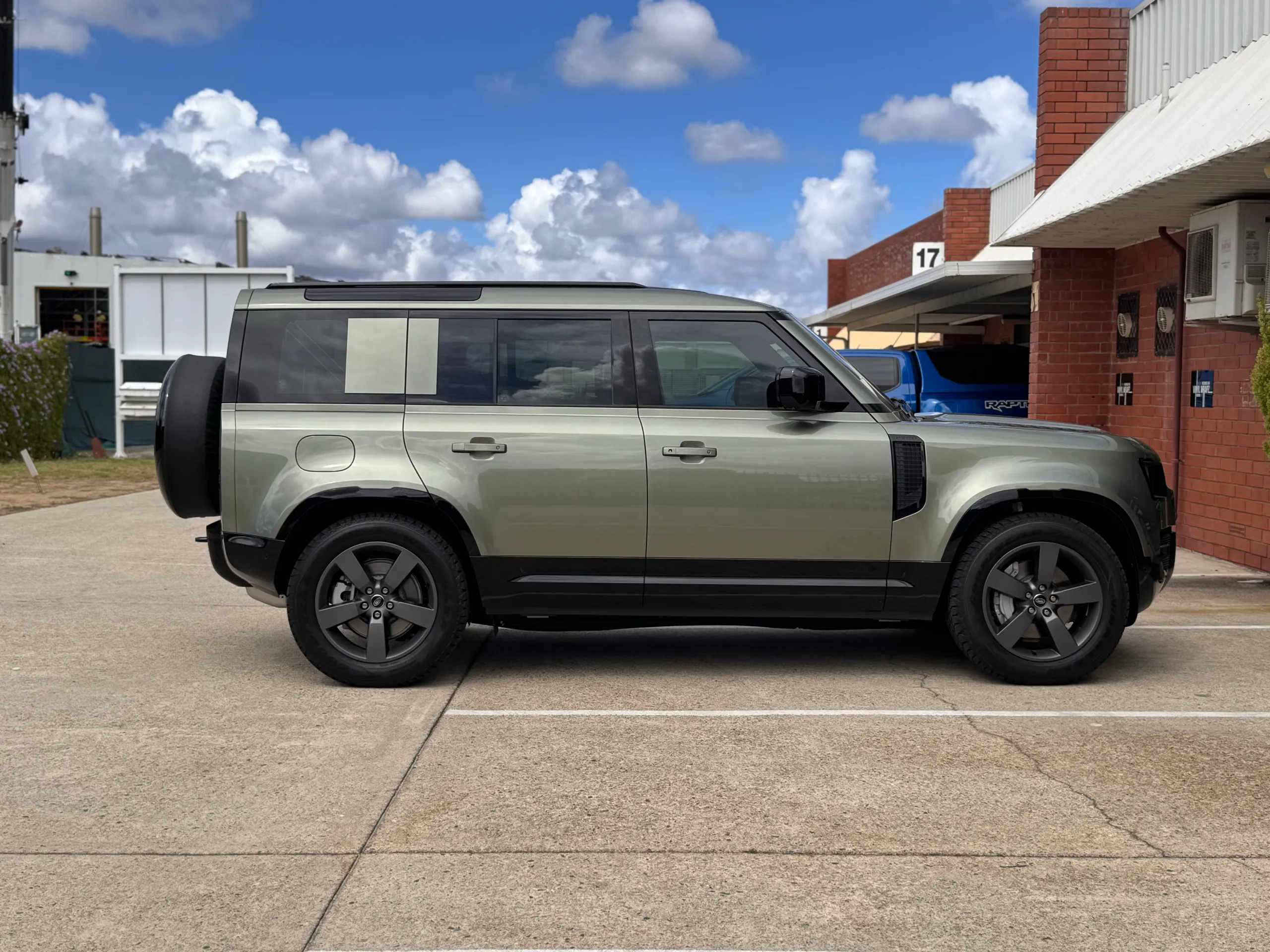 Side profile of the pale green Land Rover Defender parked outdoors