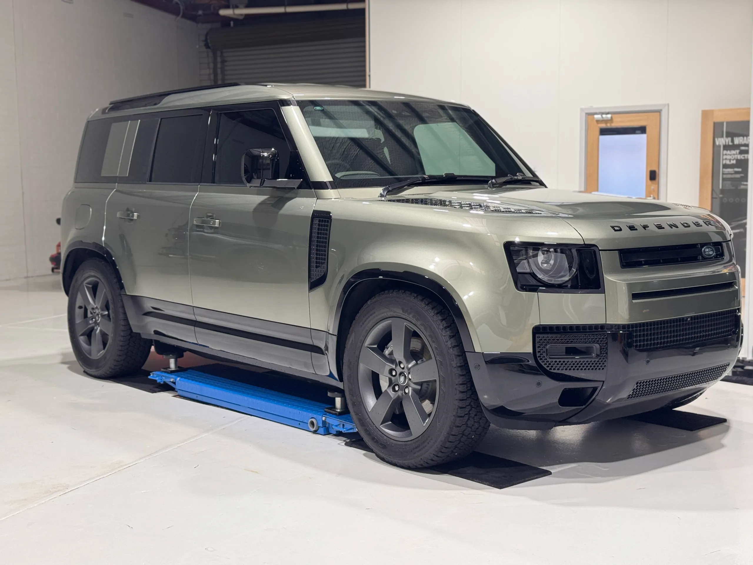 Gloss green Land Rover Defender viewed from the front quarter in the workshop