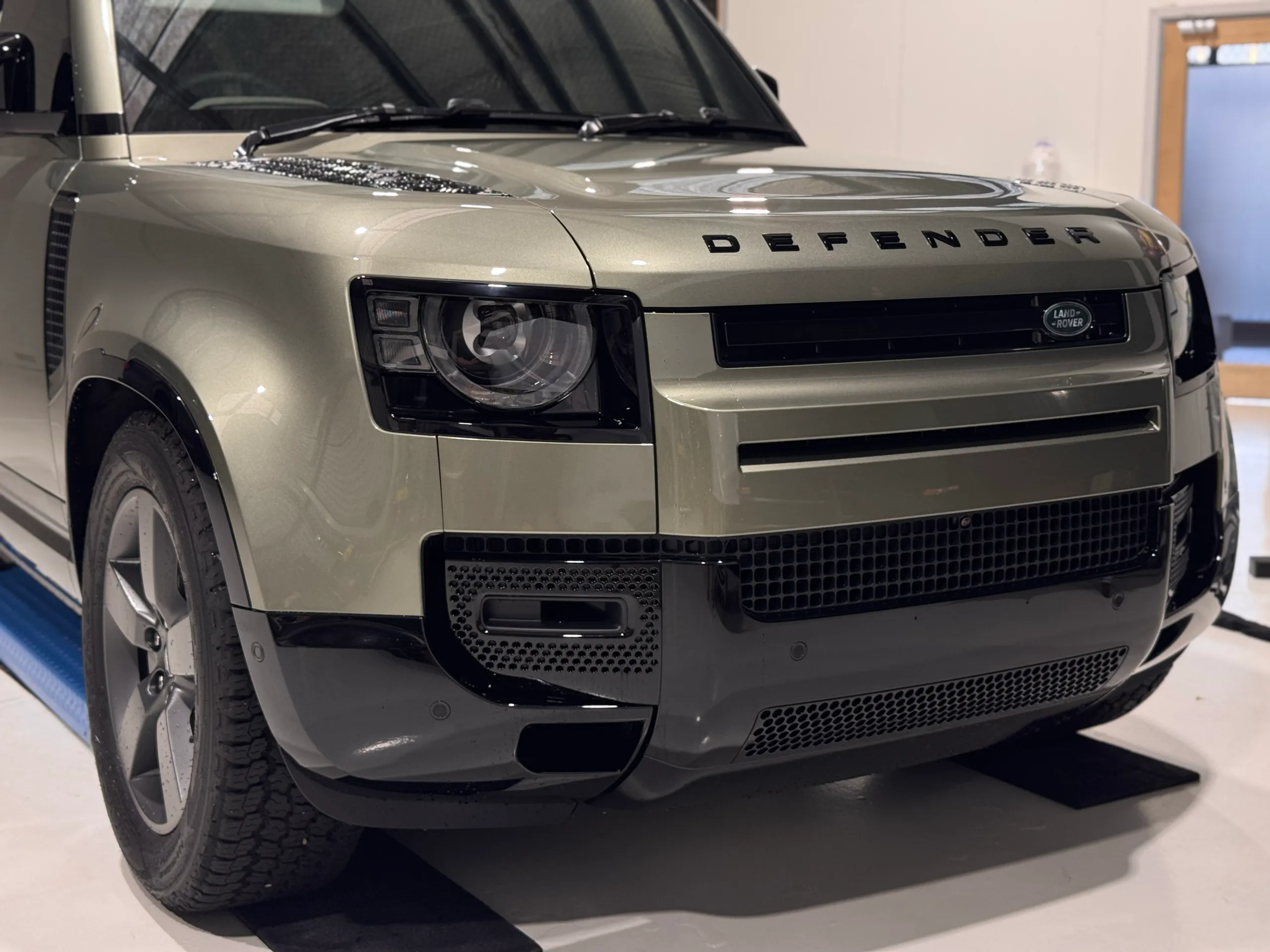 Green Defender front corner showing its bonnet lettering, headlight and grille