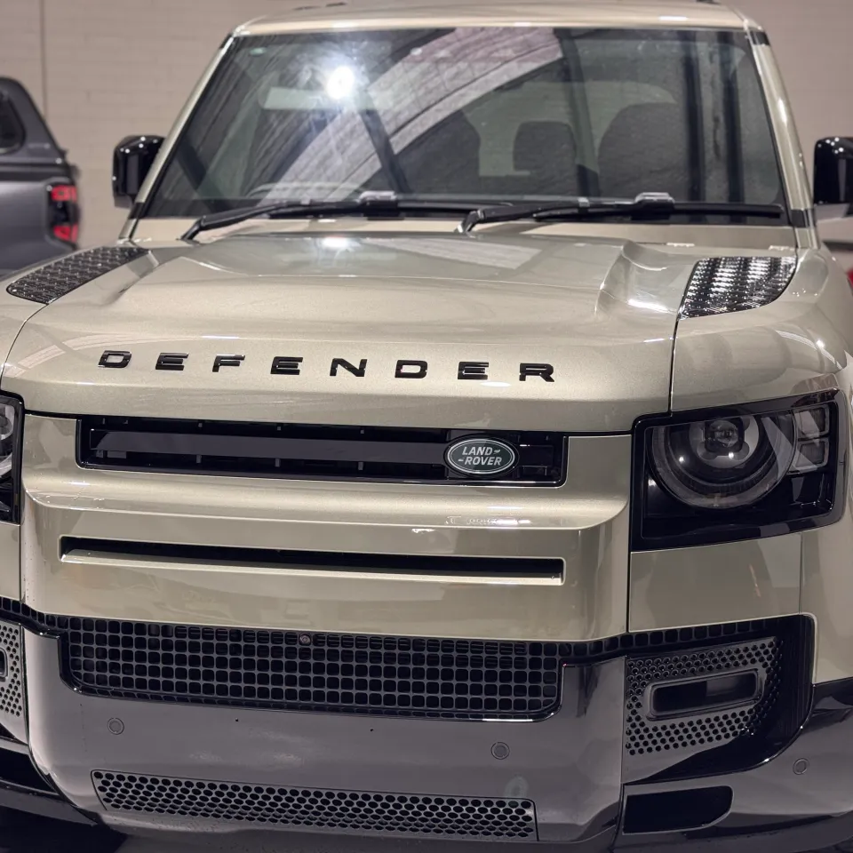 Head-on view of the green Land Rover Defender inside the workshop