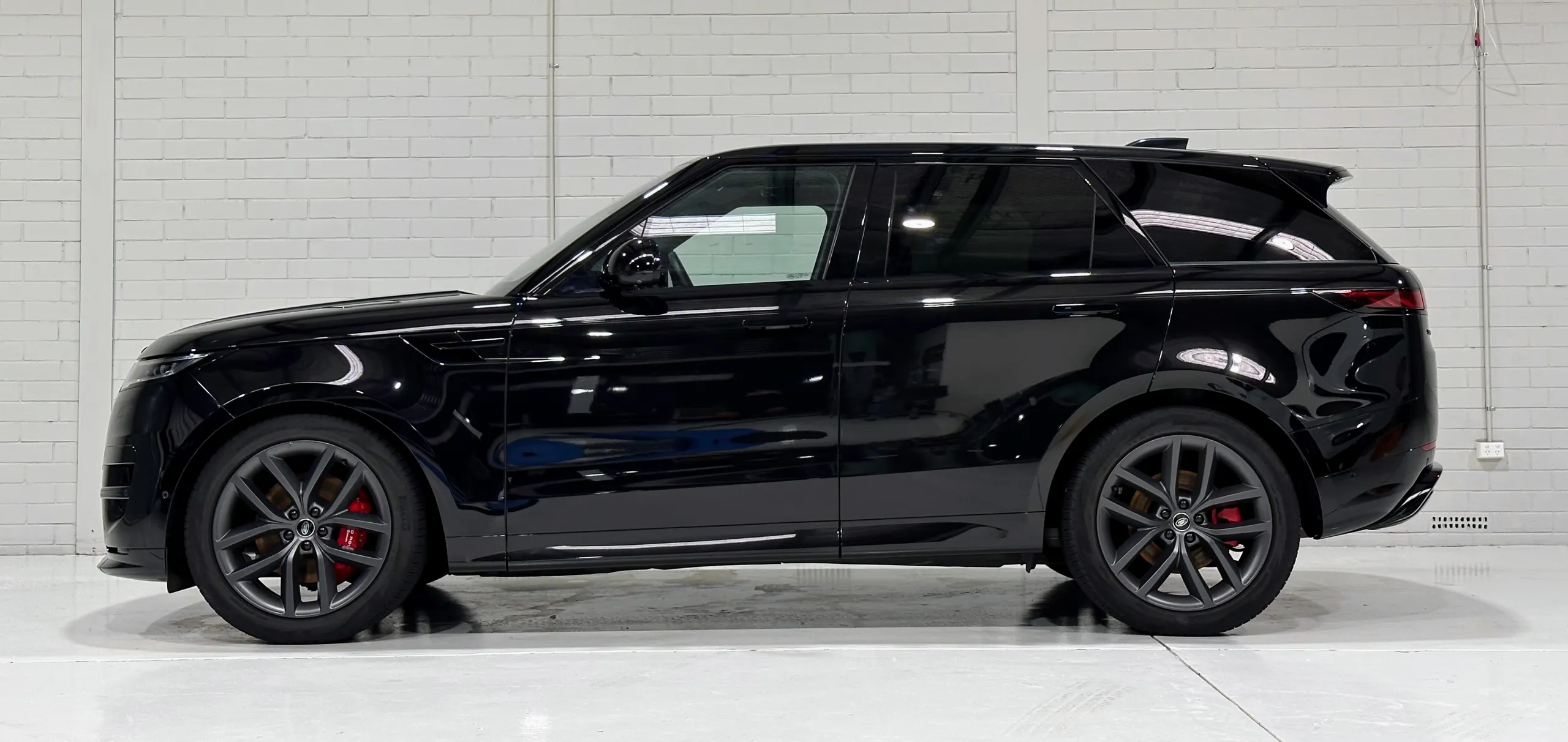 Gloss black Range Rover Sport side profile showing its red brake calipers