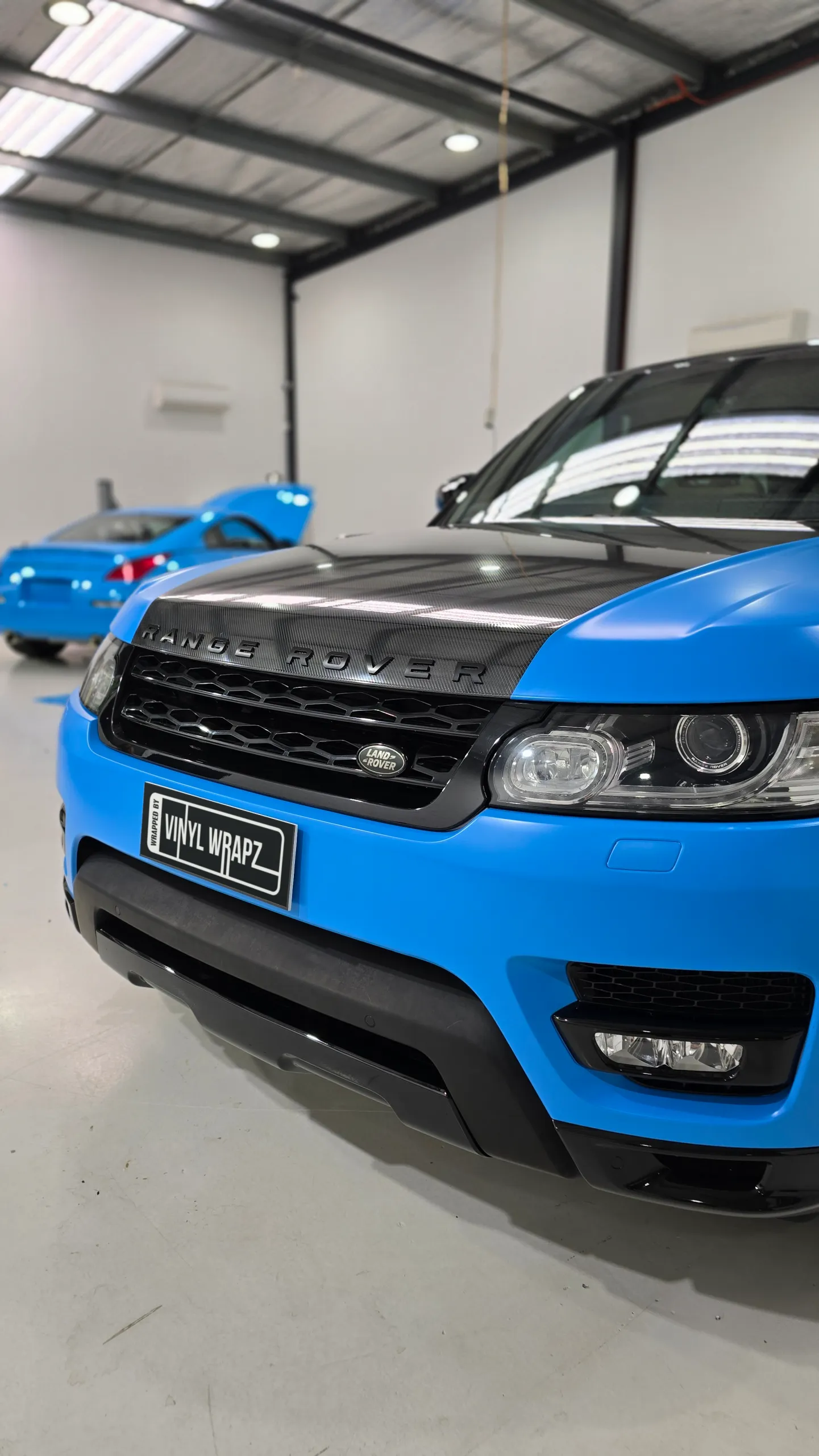 Satin blue Range Rover Sport front end with a black bonnet and grille in the workshop