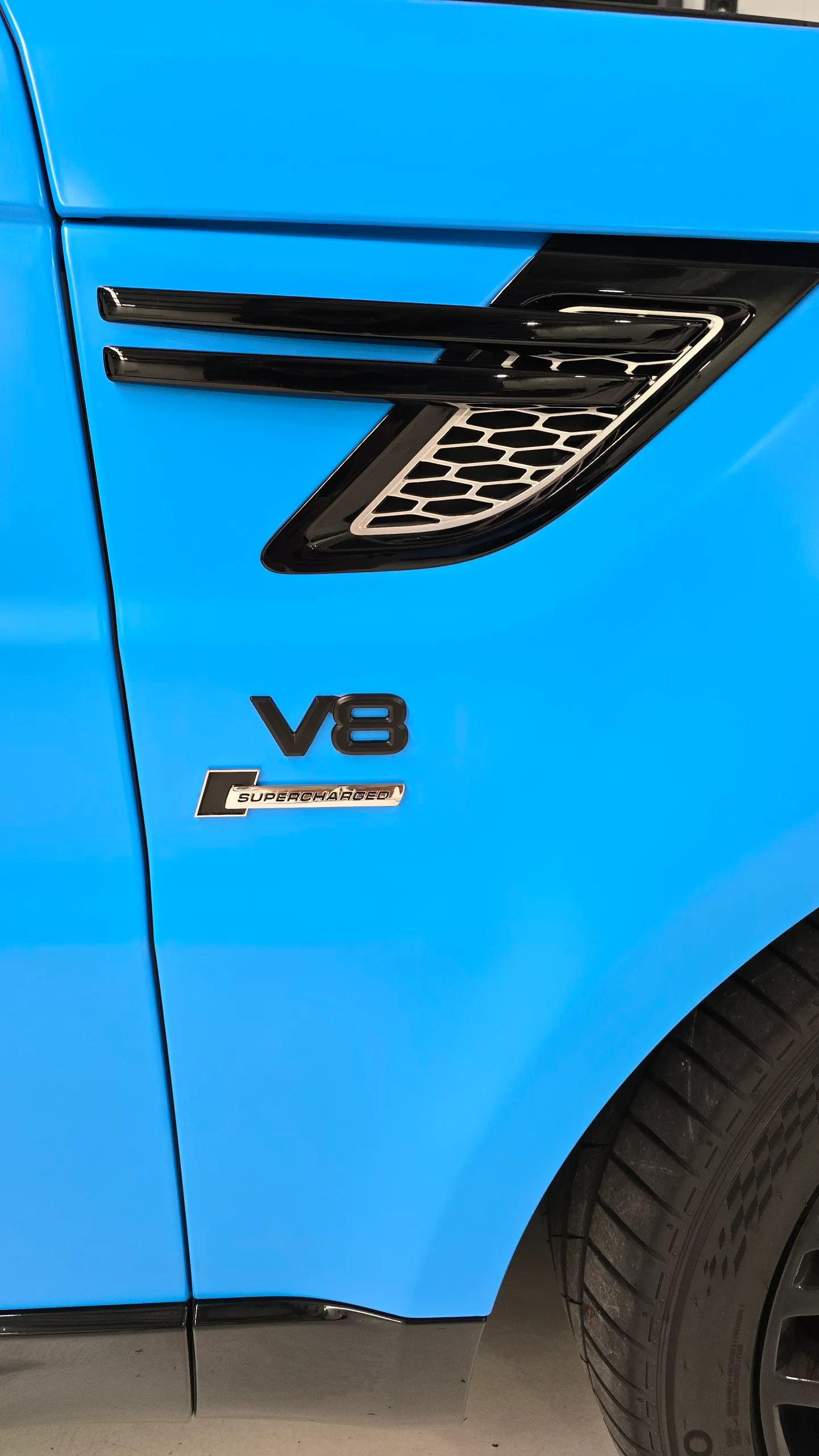 Satin light blue Range Rover Sport with black accents, side badge detail