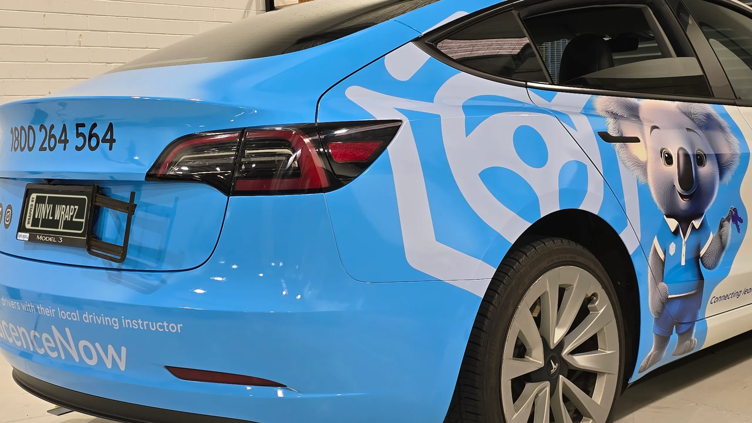 Blue LicenceNow wrap around a Tesla Model 3 rear bumper, boot and rear door in the workshop